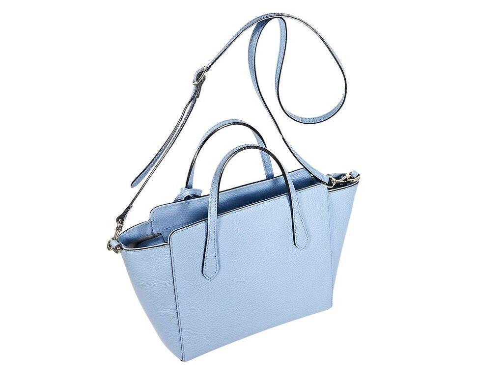 Product details:  Light blue pebbled leather Swing bag by Gucci.  Dual carry handles.  Detachable, adjustable crossbody strap.  Top zip closure.  Lined interior with inner zip and slide pockets.  Silvertone hardware.  12.5