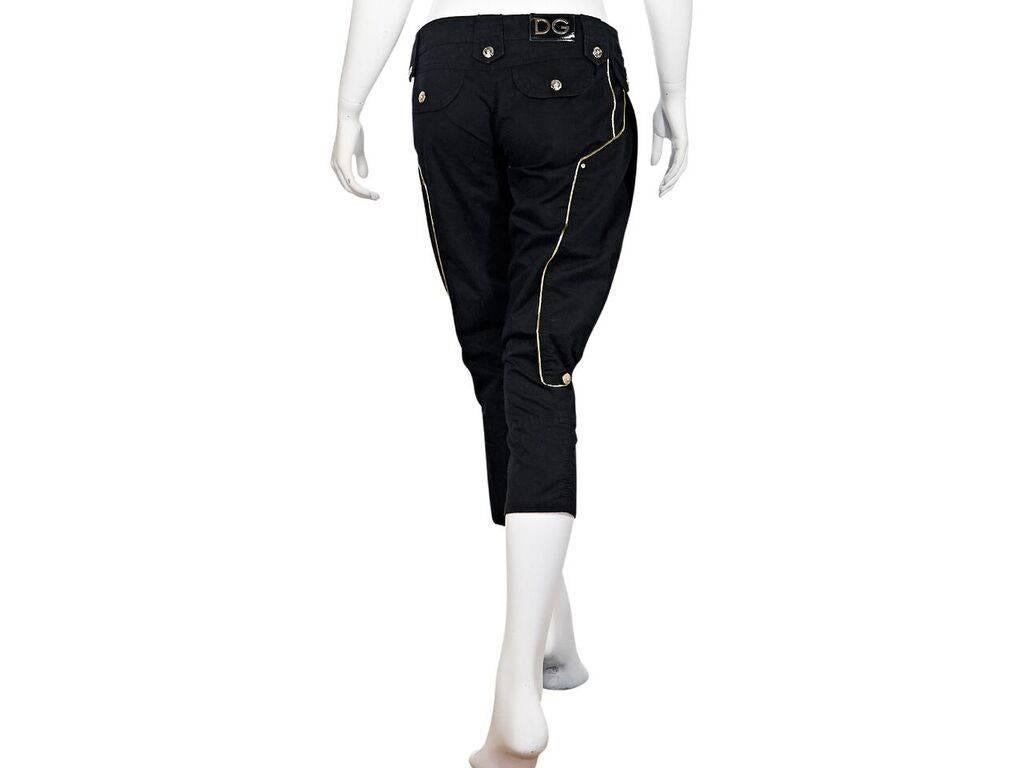 Product details:  Black cropped harem cotton pants by Dolce & Gabbana.  Accented with gold piping.  Banded waist with loops.  Button and zip fly closure.  Front and back button flap pockets.  Goldtone hardware.  28