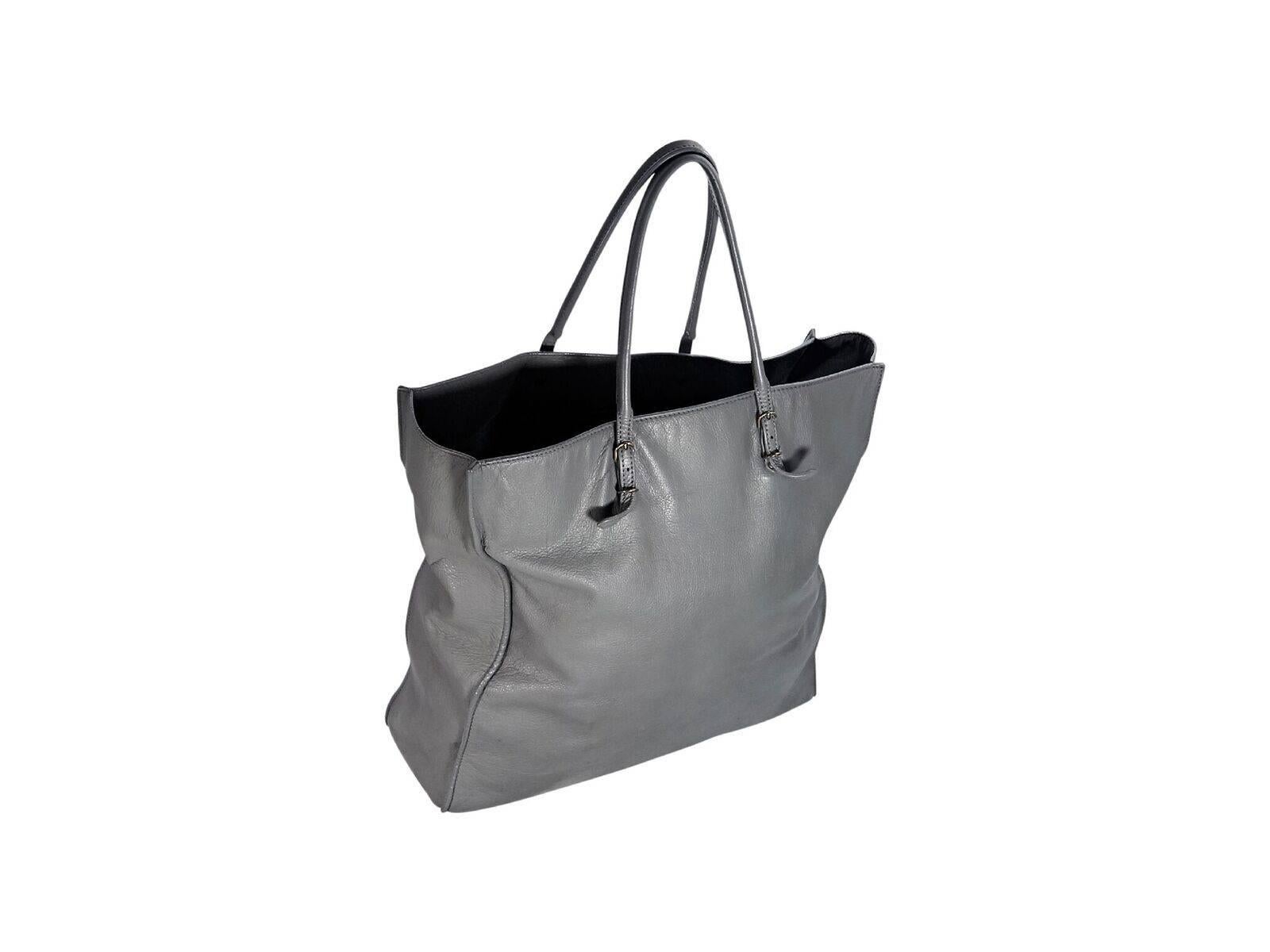 Product details:  Grey leather Papier A5 tote bag by Balenciaga.  Dual shoulder straps.  Open top.  Inner slide pockets.  Front exterior zip pocket.  Antiqued silvertone hardware.  17