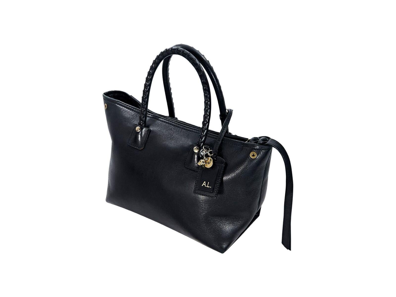Product details:  Black leather satchel by Alexander McQueen.  Accented with whipstitching.  Dual carry handles.  Detachable, adjustable shoulder strap.  Top zip closure.  Lined interior with inner zip pocket.  Exterior zip pocket.  Protective metal