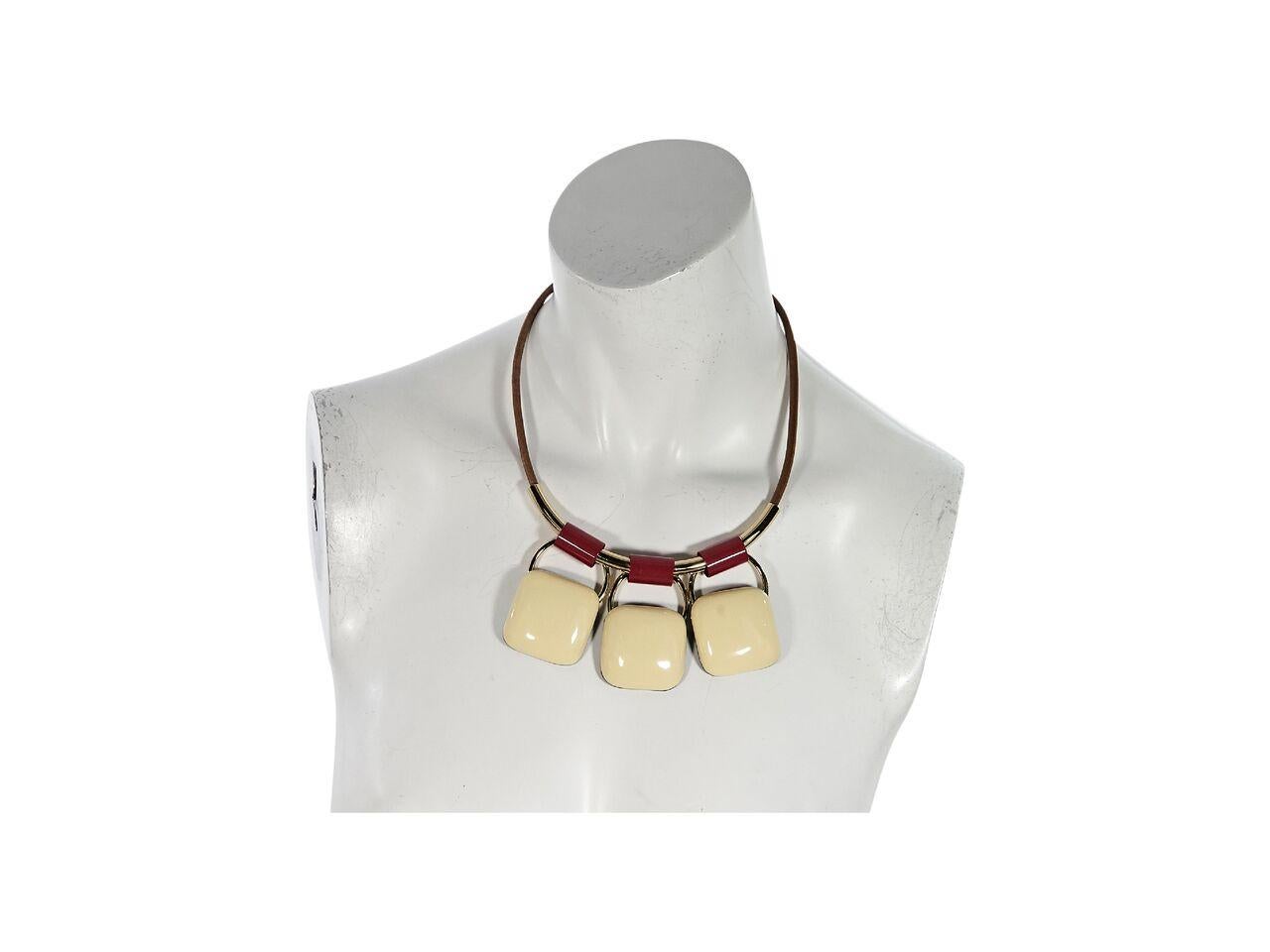 Product details:  Cream enamel pendant necklace by Marni.  Adjustable closure.  Leather string.  Goldtone and red hardware.  20
