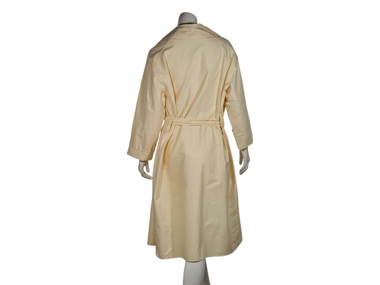 Product details:  Cream waterproof cotton trench coat by The Row.  Notched lapel.  Long sleeves.  Concealed front closure.  Self-tie belted waist.  46