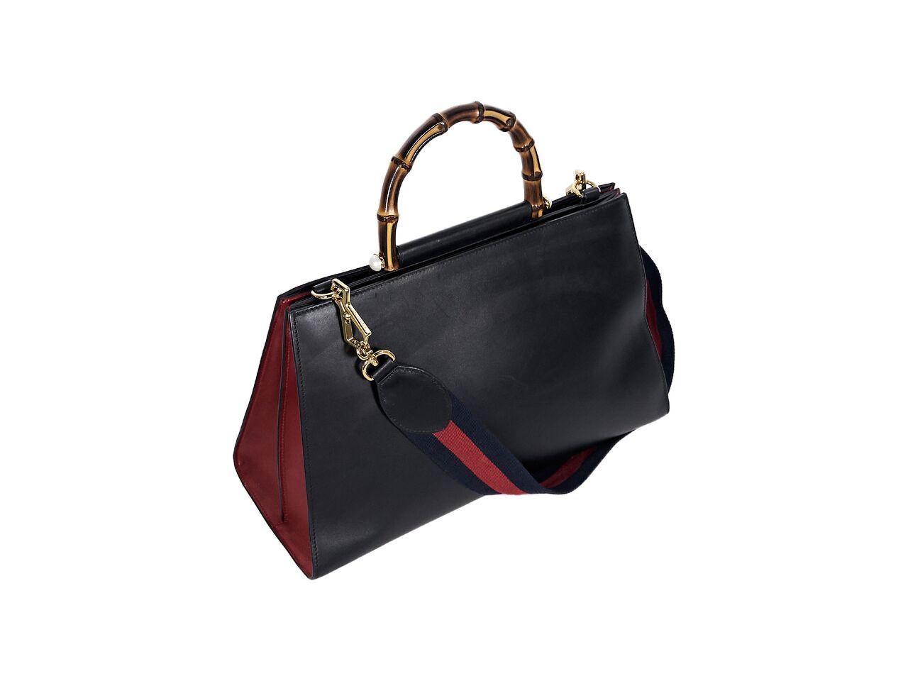 Product details:  Black and red leather Nymphea satchel by Gucci.  Top bamboo handle.  Detachable shoulder strap.  Concealed magnetic closure.  Lined interior with inner zip and slide pockets.  Goldtone hardware.  13.5