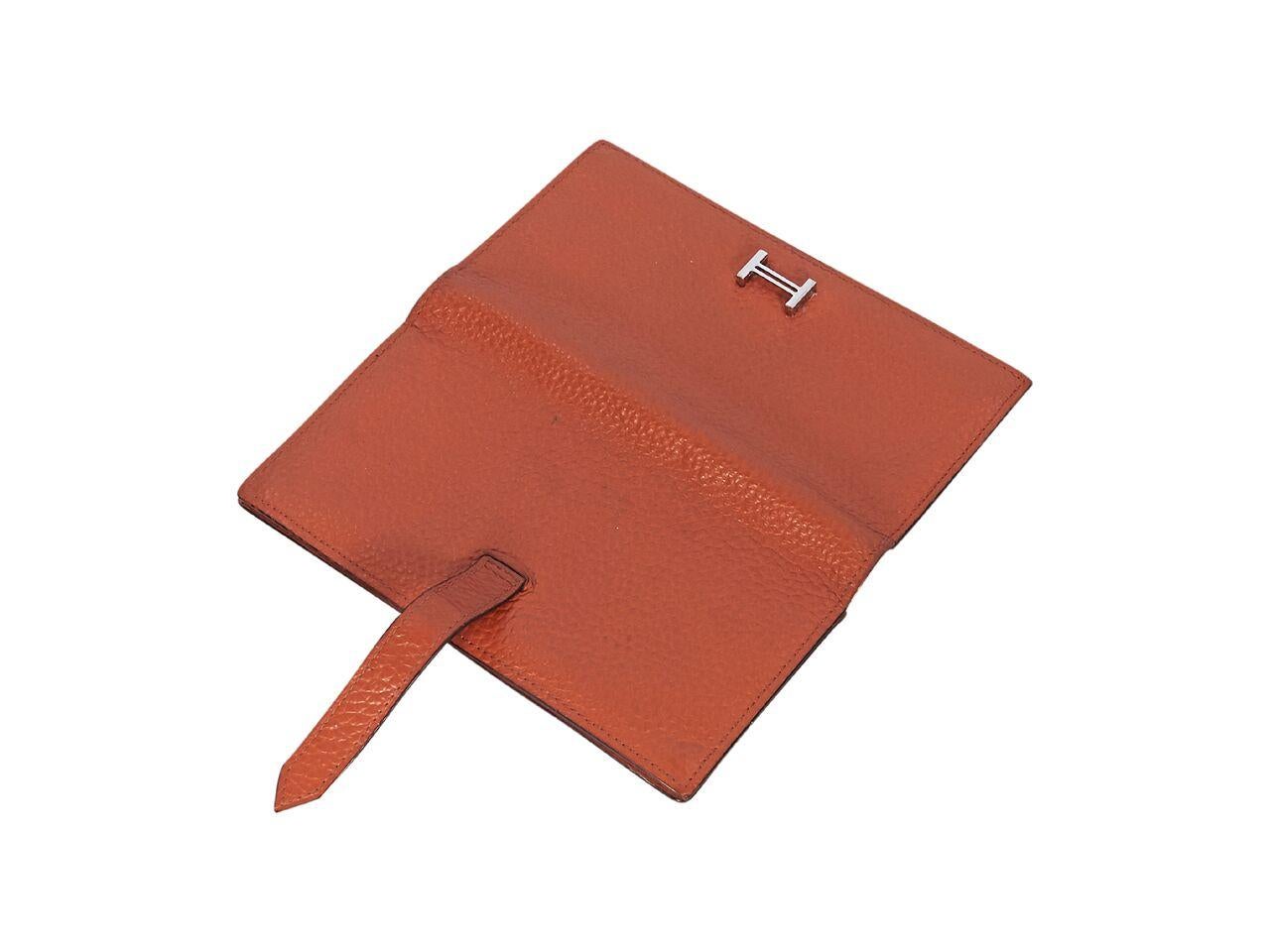 Product details:  Orange Bearn epsom pebbled leather wallet by Hermes.  Tab closure.  Leather interior with zip coin pouch, multiple credit card slots and bill compartments.  Silvertone hardware.  Original box included. 
Condition: Pre-owned. Very