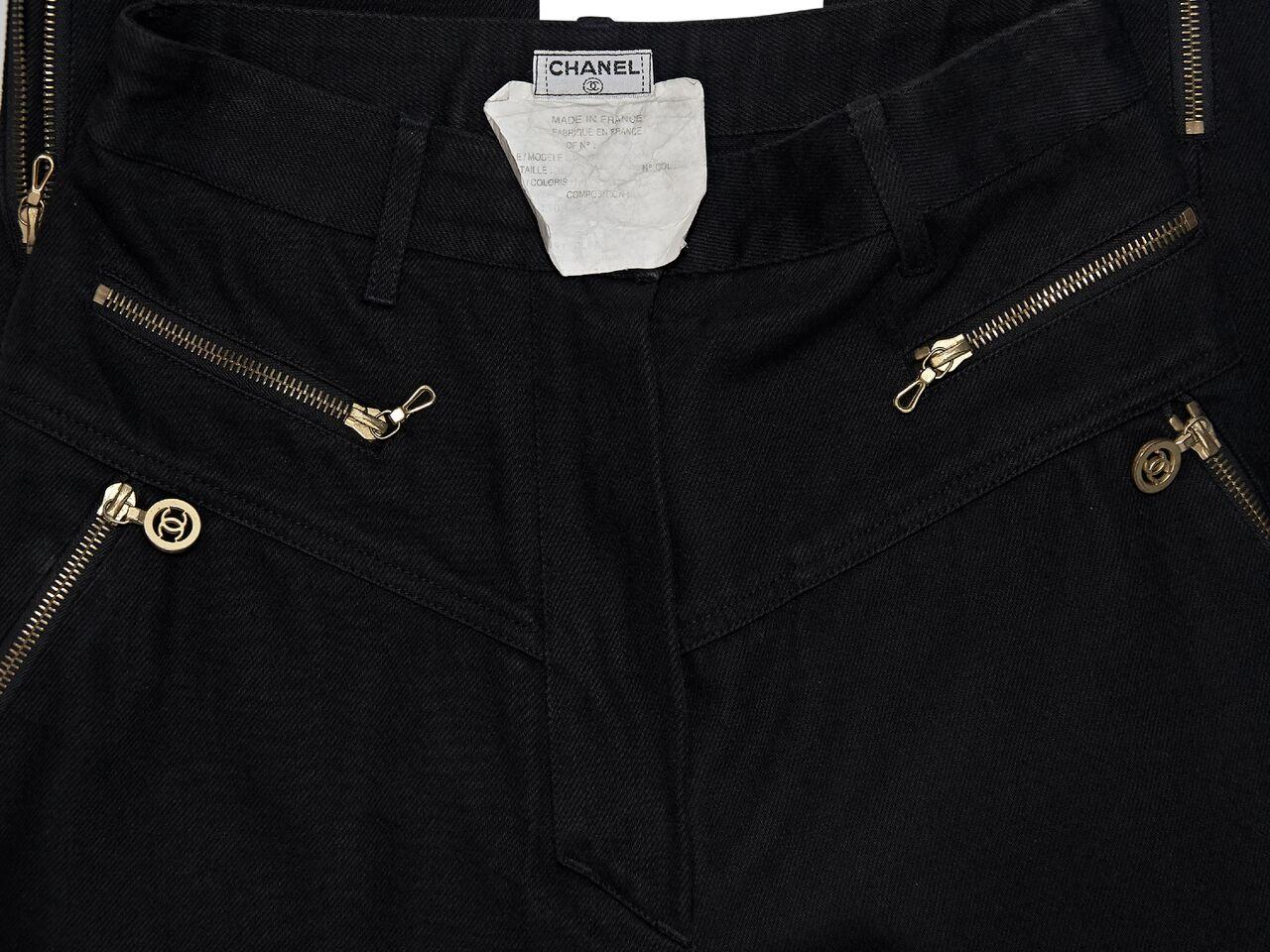 Product details:  Vintage black denim pants by Chanel.  Banded waist with belt loops.  Button and zip fly closure.  Front zip pockets.  Back patch pockets.  Zip hem.  Goldtone hardware.  26.5