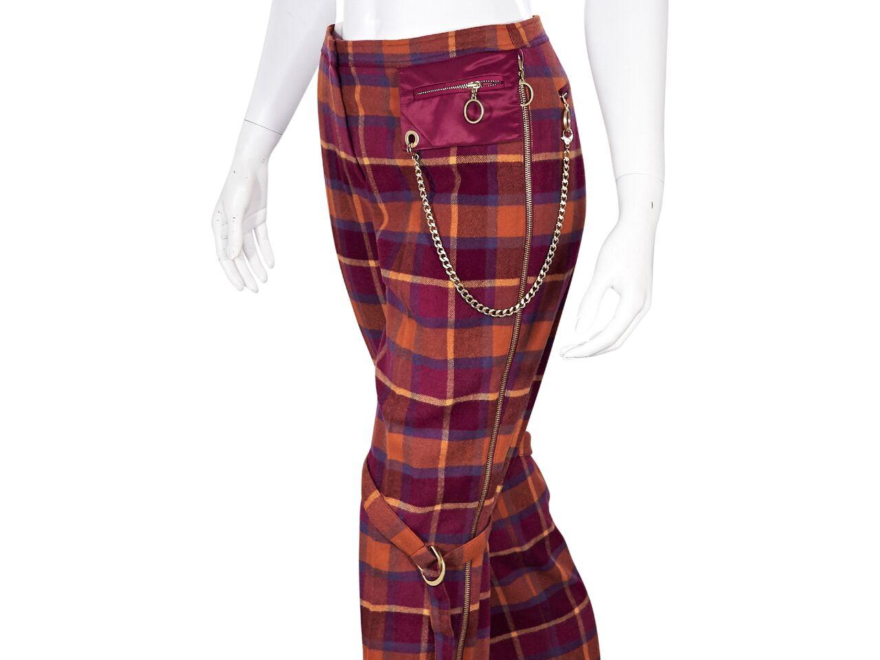 Product details:  Red tartan plaid wool pants by Escada Sport.  Banded waist.  Concealed hook and zip fly closure.  Side zip pocket with chain detail.  Adjustable straps at knees.  Side zipper placket accent.  Pull-on style.  Goldtone hardware.  31