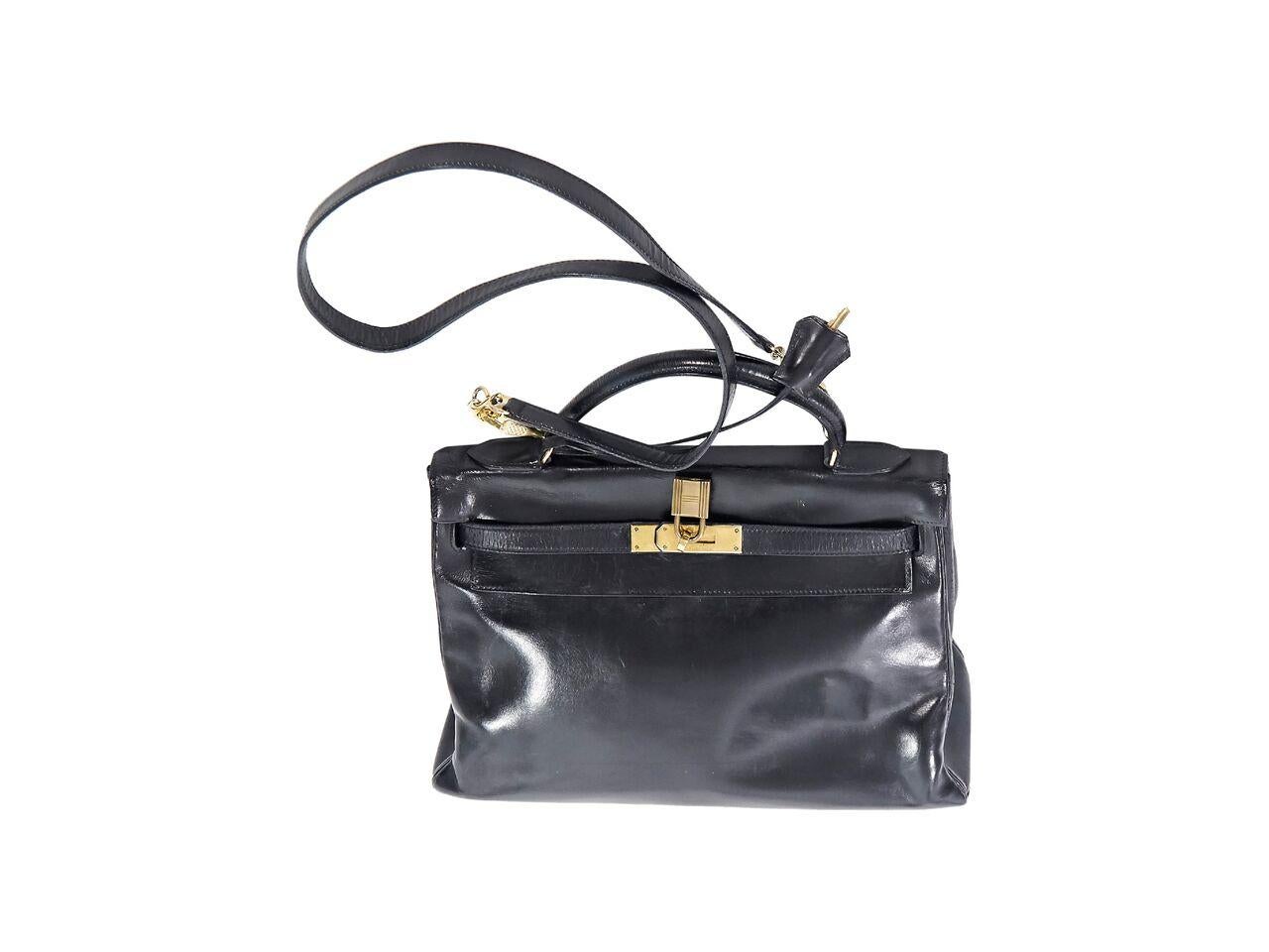 Product details:  Vintage black Kelly Retourne 28cm leather satchel by Hermes.  Top carry handle.  Detachable crossbody strap.  Front flap with lock and key closure.  Leather lined interior with inner zip and slide pockets.  Protective metal feet. 