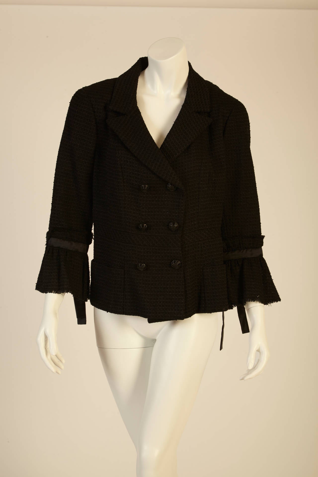 With its beautiful tweed fabric,this delicate black jacket is gorgeous and versatile.  Its ruffled sleeves are tied with a beautiful bow and has three pairs of impeccably embellished buttons. You are bound to look flawless no matter what the