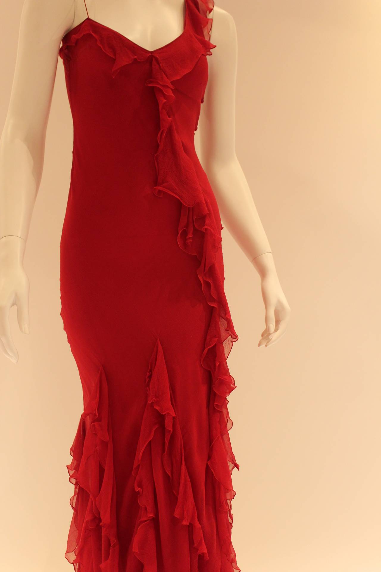 This one-shoulder, diva-worthy red gown is absolutely flawless. Gorgeous ruffles line the single shoulder and neckline. From the center of the neckline, they trail down the left hip to form a stunning array of ruffles at the bottom. Contains