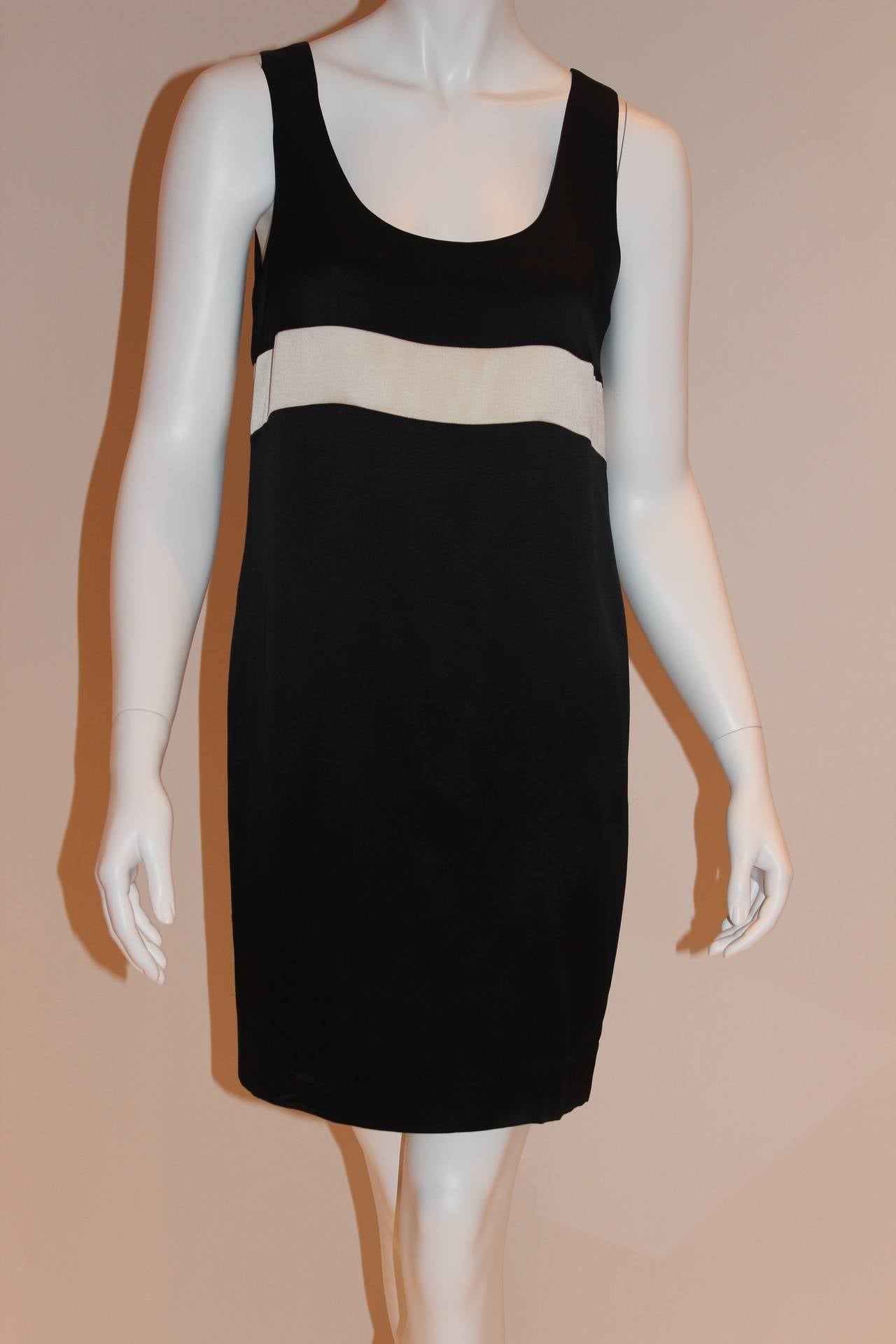 This sleeveless, straight-cut black and white silk Chanel dress contains a subtle, scoop neckline and a thick white stripe that circles around entirely. Dress is knee-length and in excellent, barely worn condition.