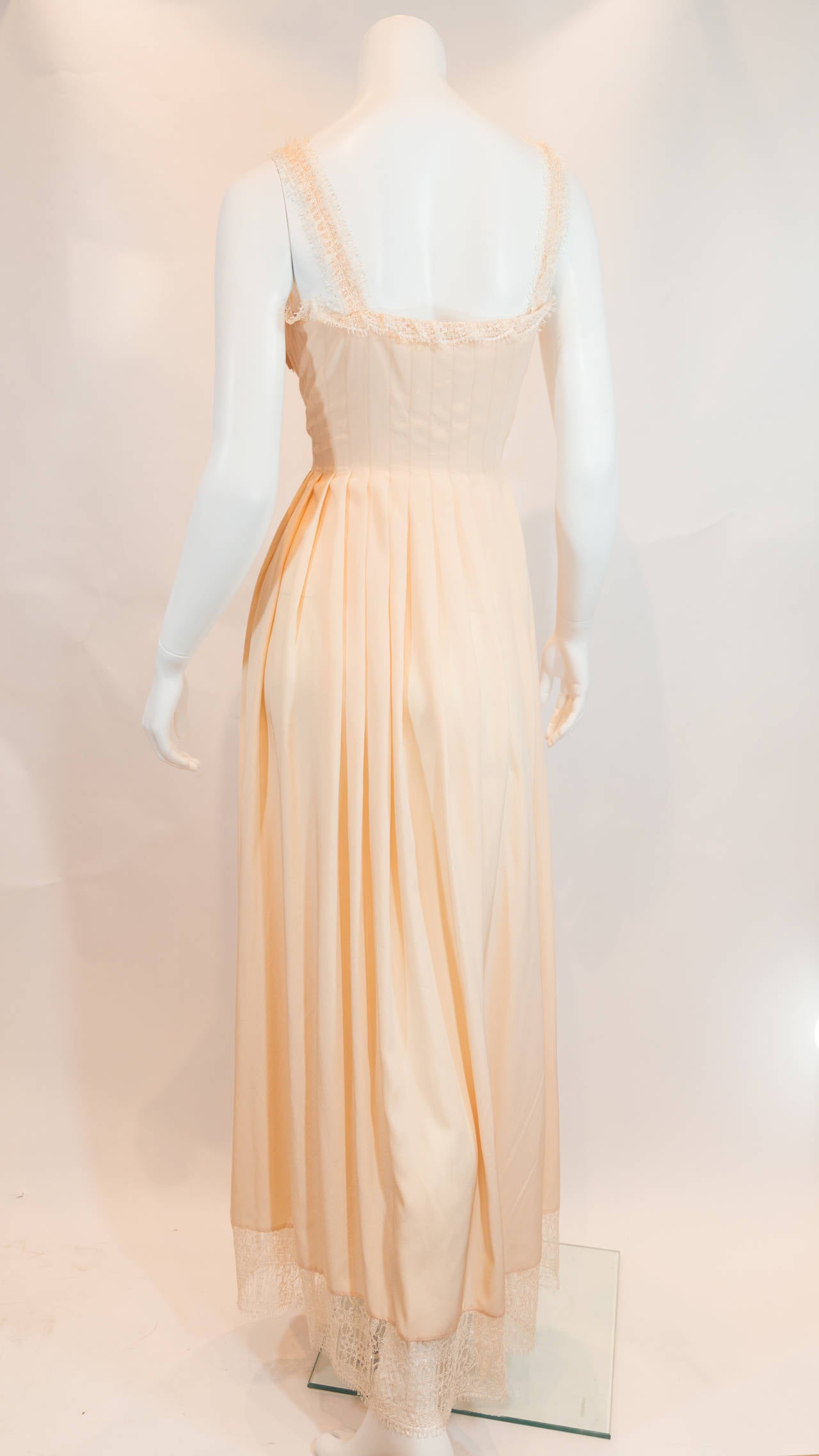 This soft-colored, floor-length evening dress is absolutely breathtaking. Contains subtle pleats – beginning at the midline – throughout its entire inferior portion and is lined with lace trim on the neckline, shoulder straps, and bottom.