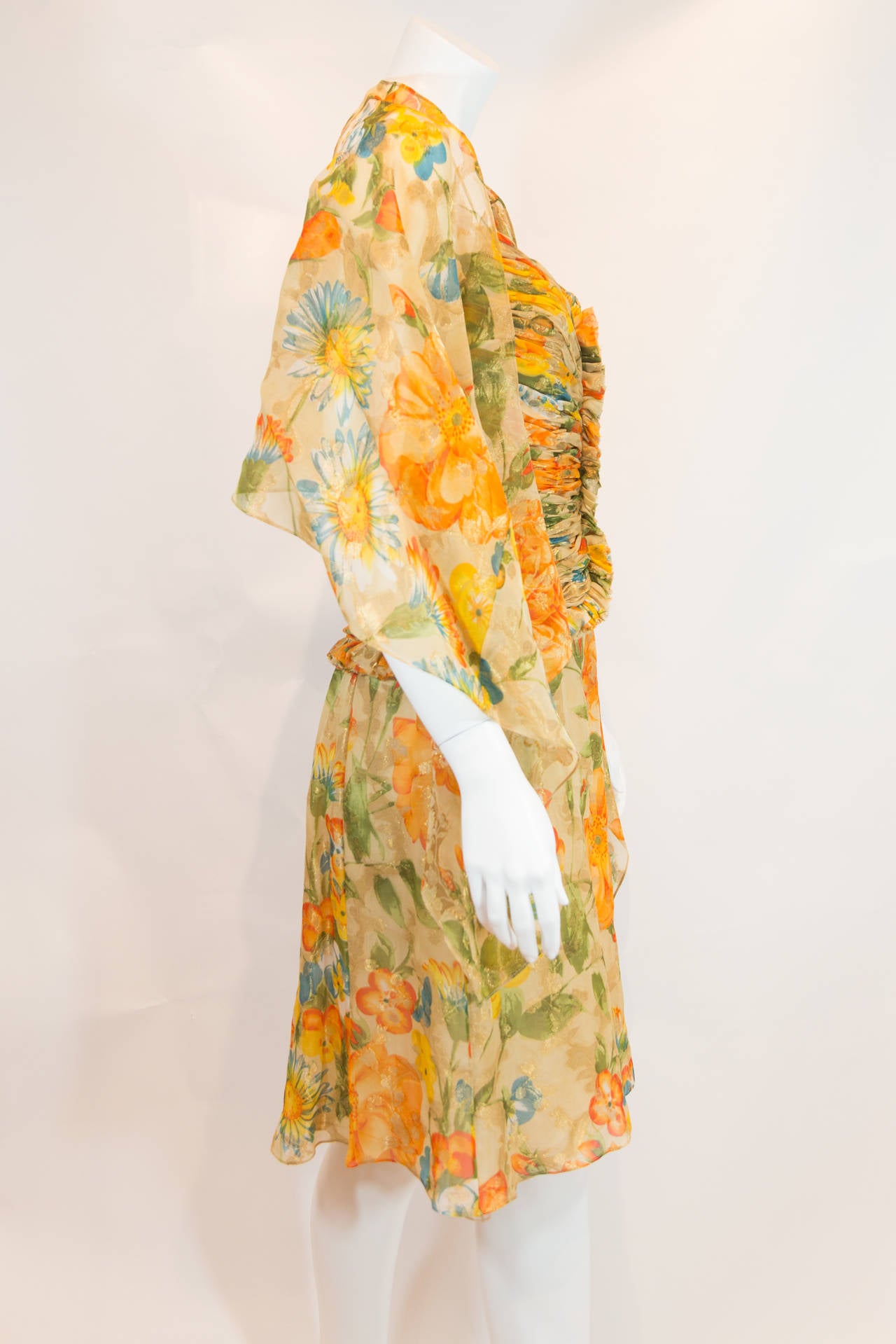 This printed gown is absolutely flawless. Its gathered material forms a complimentary cinch down the midline. Contains impeccable floral print, a gorgeous V-neckline, and a matching scarf that can be draped over the gown in any preferred fashion.