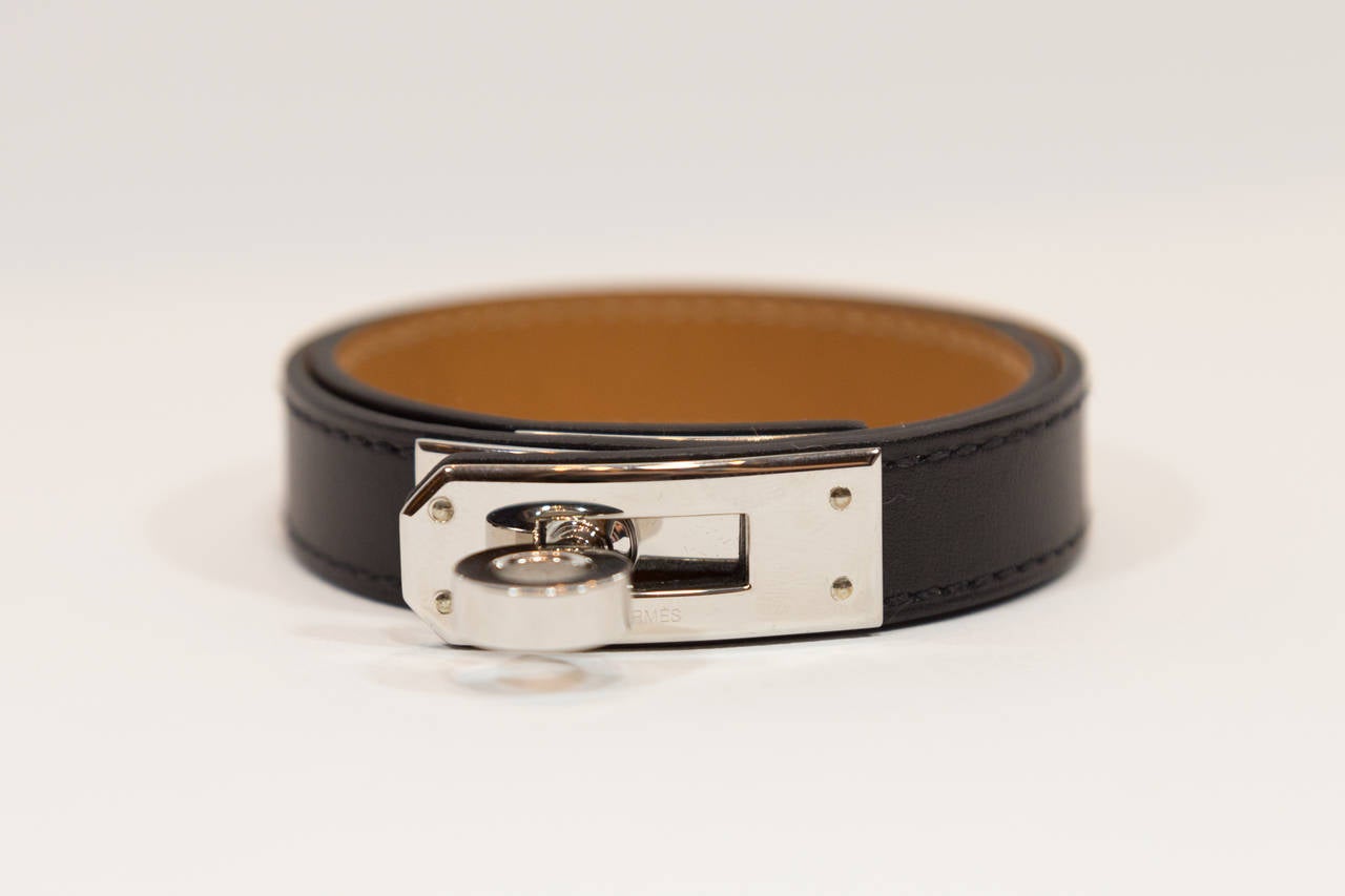This authentic Hermes Kelly bracelet adds a simple and stylish statement to any ensemble. Contains palladium plated hardware and is interiorly engraved with the Hermes logo. Adjustable and closes with a single notch. Never been worn and comes with