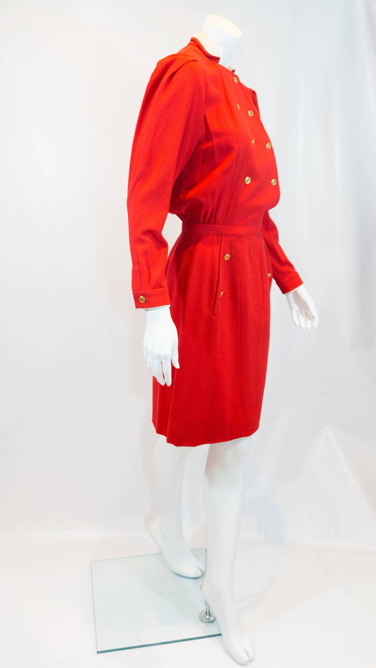 Chanel vintage red dress that is double breasted and has 7 front buttons, button detail on sleeve, and the skirt section has 2 side slit pockets with 2 button detail on each. Collar is lined in white silk.