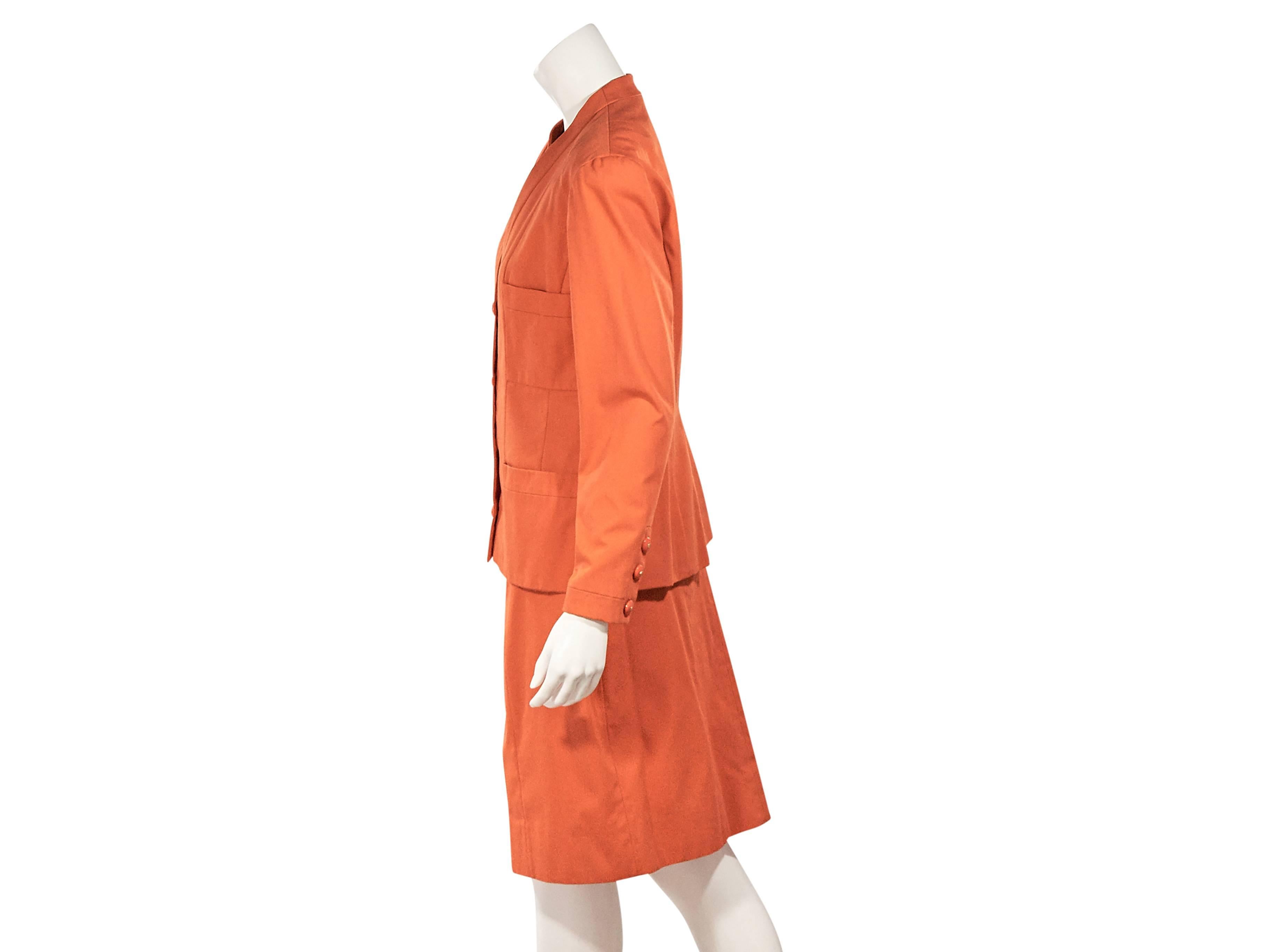 Product details:  Orange vintage skirt suit set by Chanel.  V-neck.  Long sleeves.  Three-button detail at cuffs.  Chest and waist patch pockets.  Seams at back create a flattering silhouette.  Matching pencil skirt.  Banded waist.    
Condition: