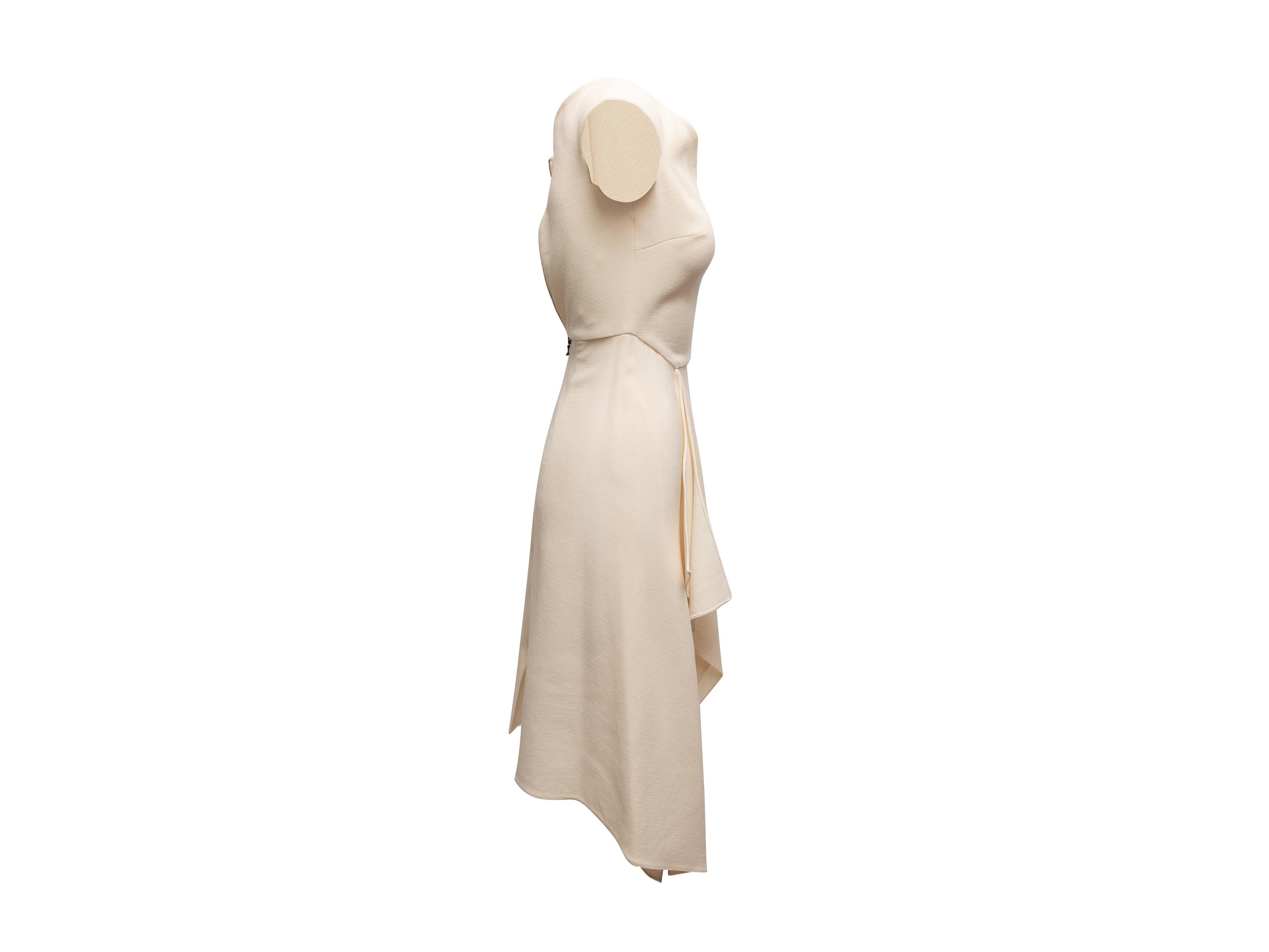Robe asymétrique sans manches en laine crème par Roland Mouret. Encolure géométrique. Fermeture à glissière au dos. Buste de 29