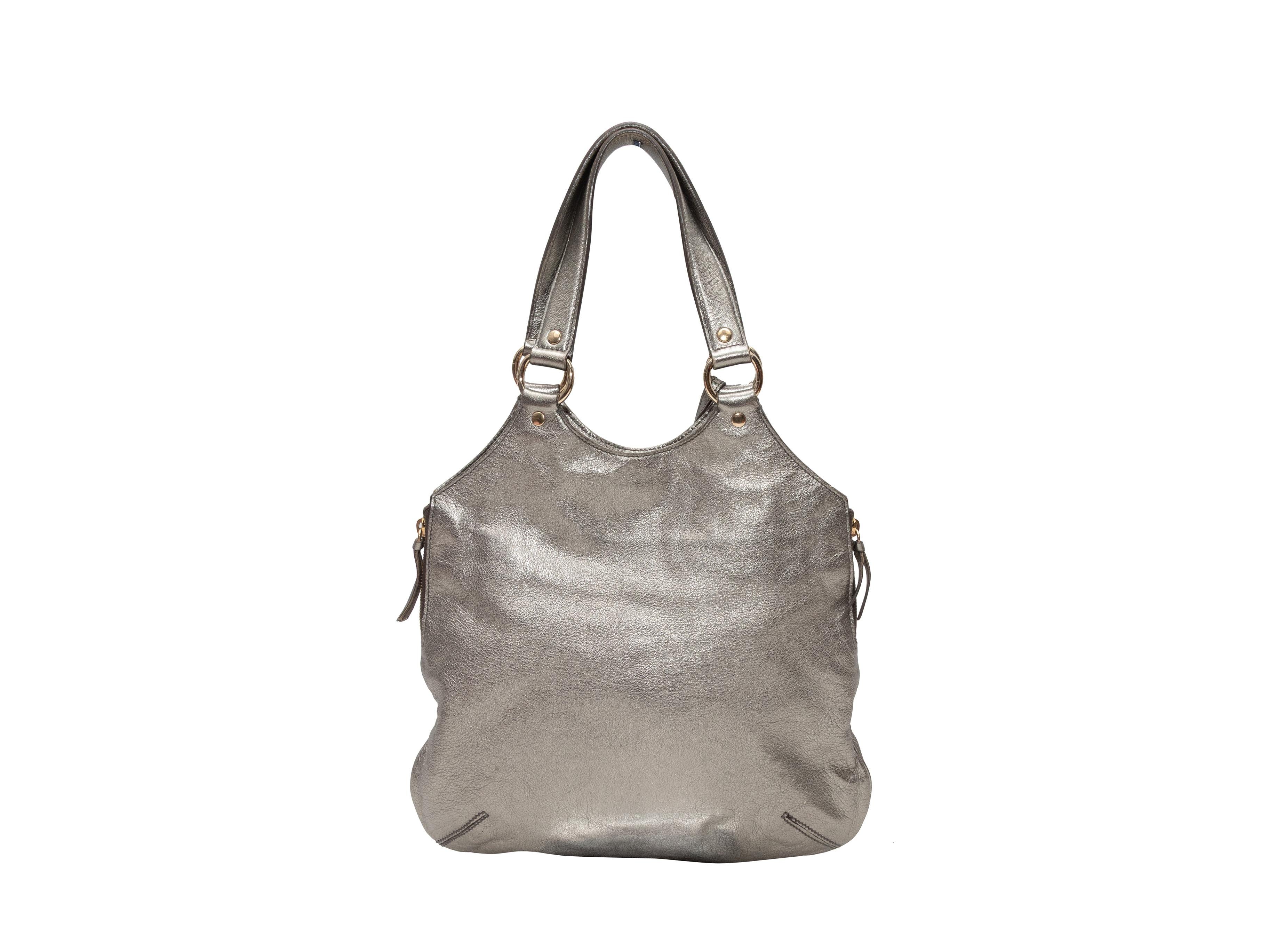  Yves Saint Laurent Small Tribute Tote in argento. La Small Tribute Tote è caratterizzata da un corpo in pelle, finiture dorate, doppia tracolla piatta, zip laterale e chiusura magnetica superiore. 13,25