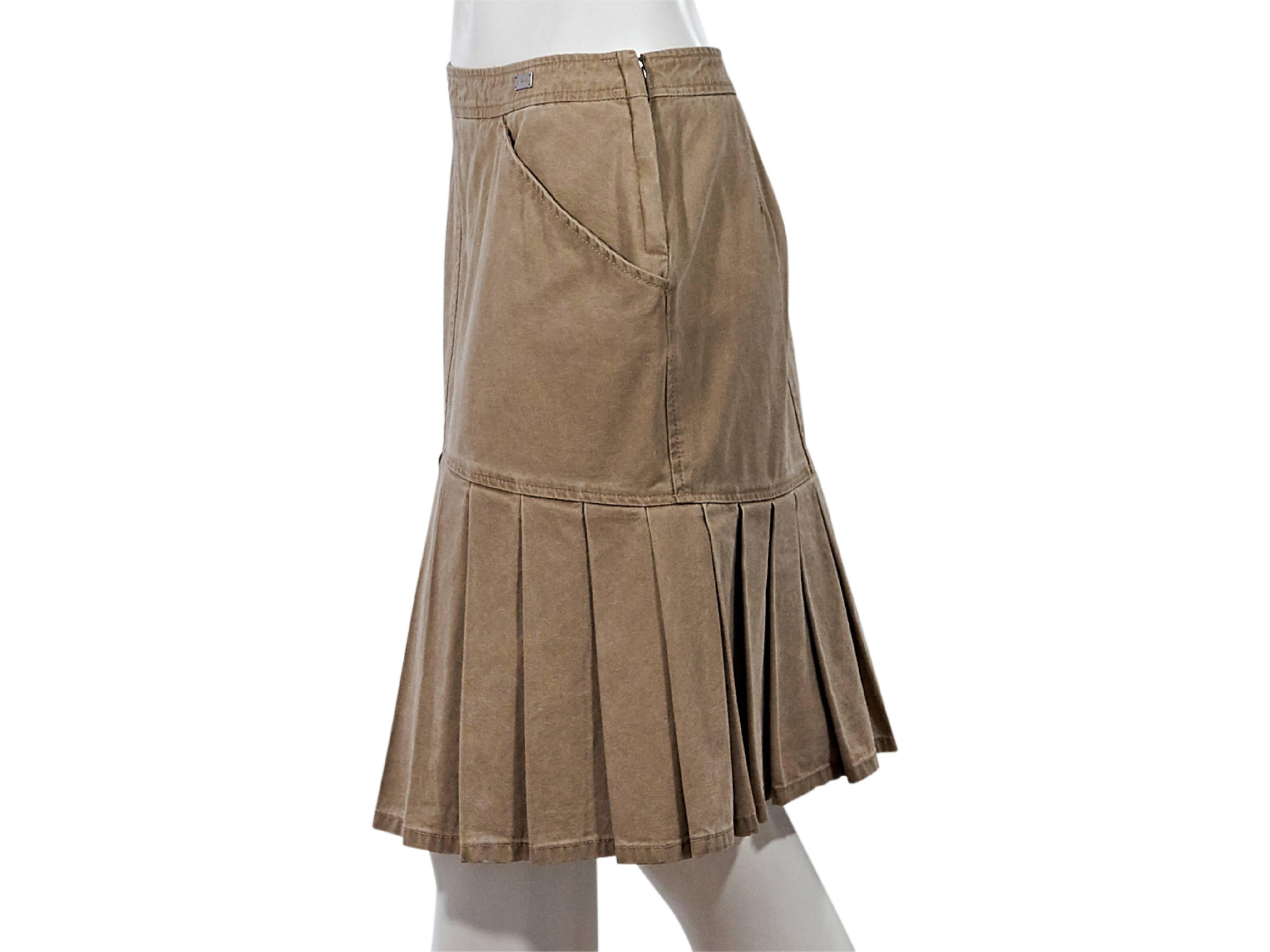 Product details:  Tan denim skirt by Chanel.  Banded waist.  Waist slant slide pockets.  Concealed side zip closure.  Box pleated hem. 
Condition: Pre-owned. Very good.
Est. Retail: $ 1,500.00