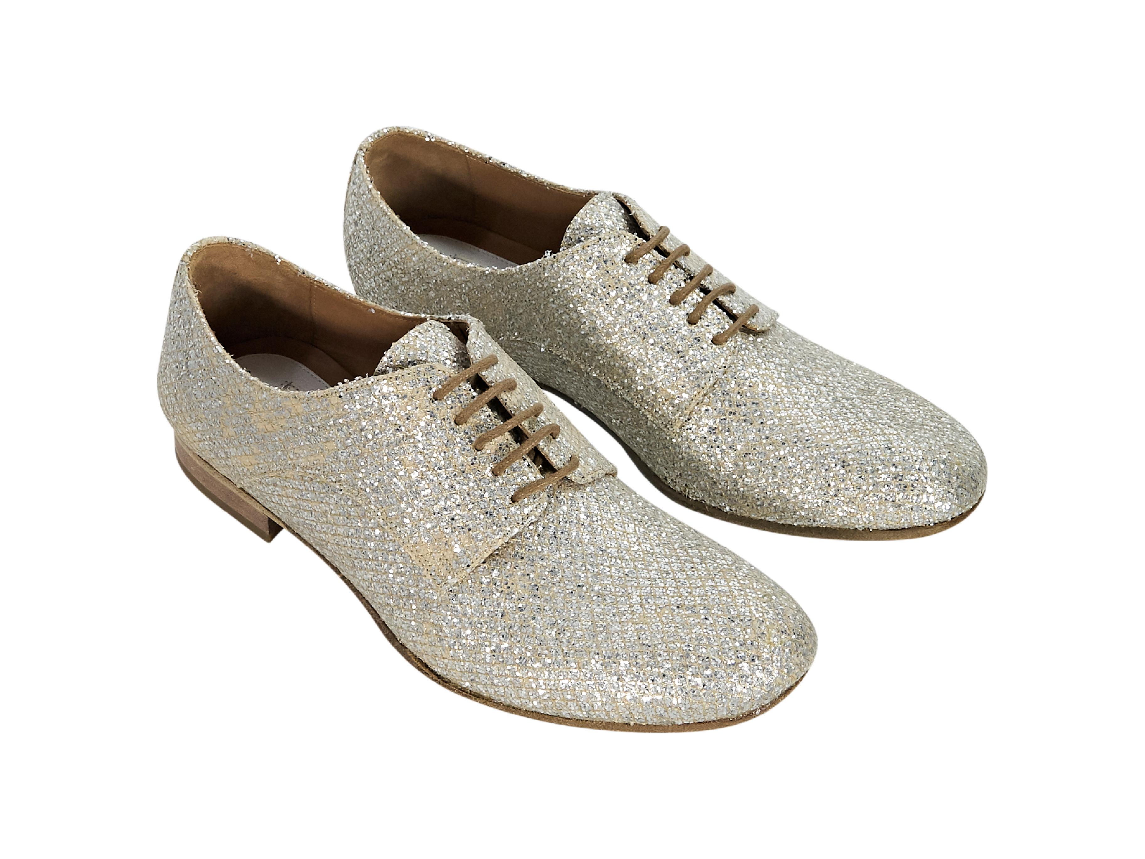 Product details:  Silver glittered oxford shoes by Maison Martin Margiela.  Lace-up closure.  Round toe.  Low stacked heel. 
Condition: Pre-owned. Very good. Slight discoloration.
