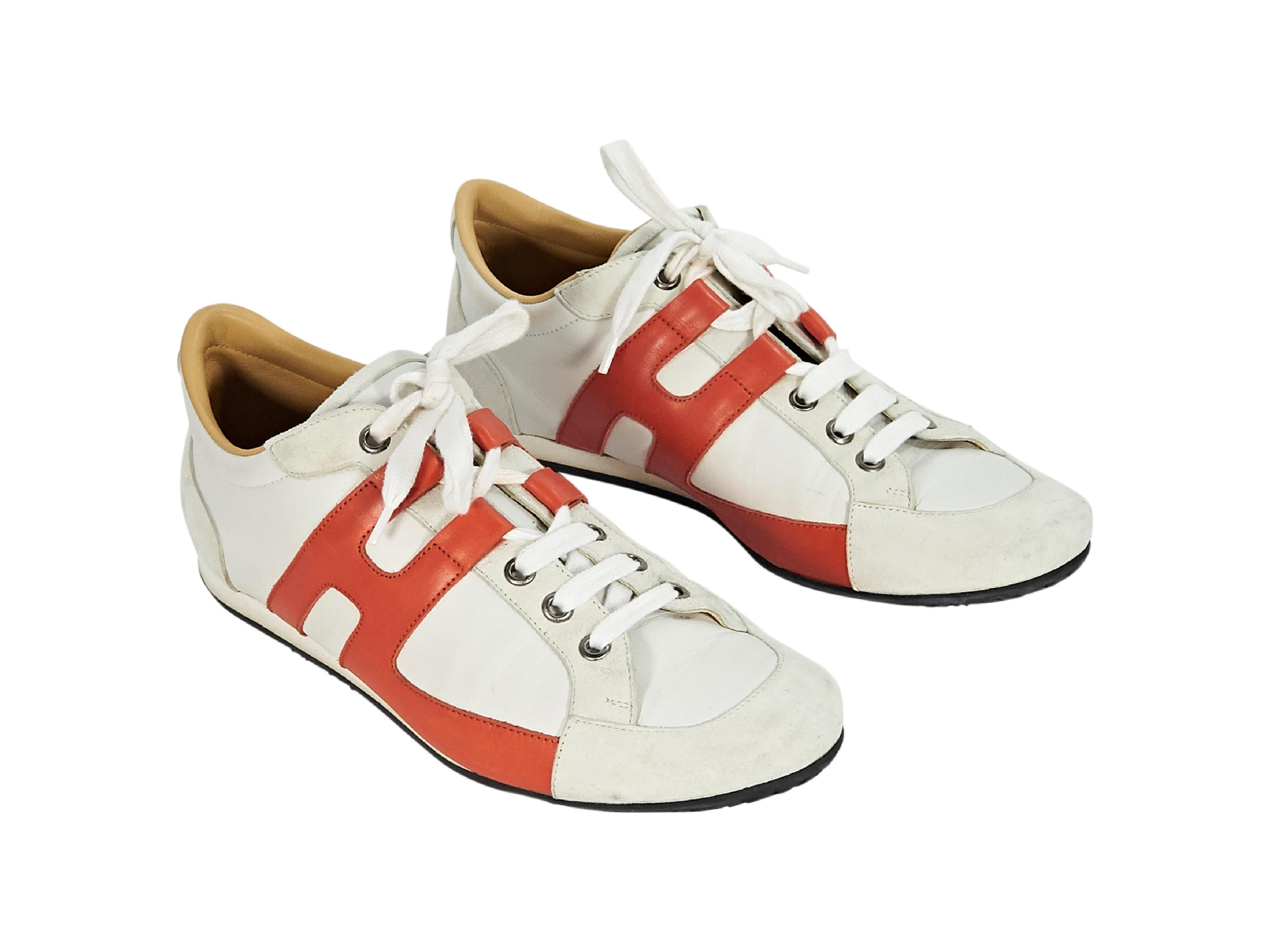 Product details:  White and orange leather sneakers by Hermes.  Trimmed with suede.  Lace-up closure.  Round toe. 
Condition: Pre-owned. Good. 
Est. Retail $ 1,125.00