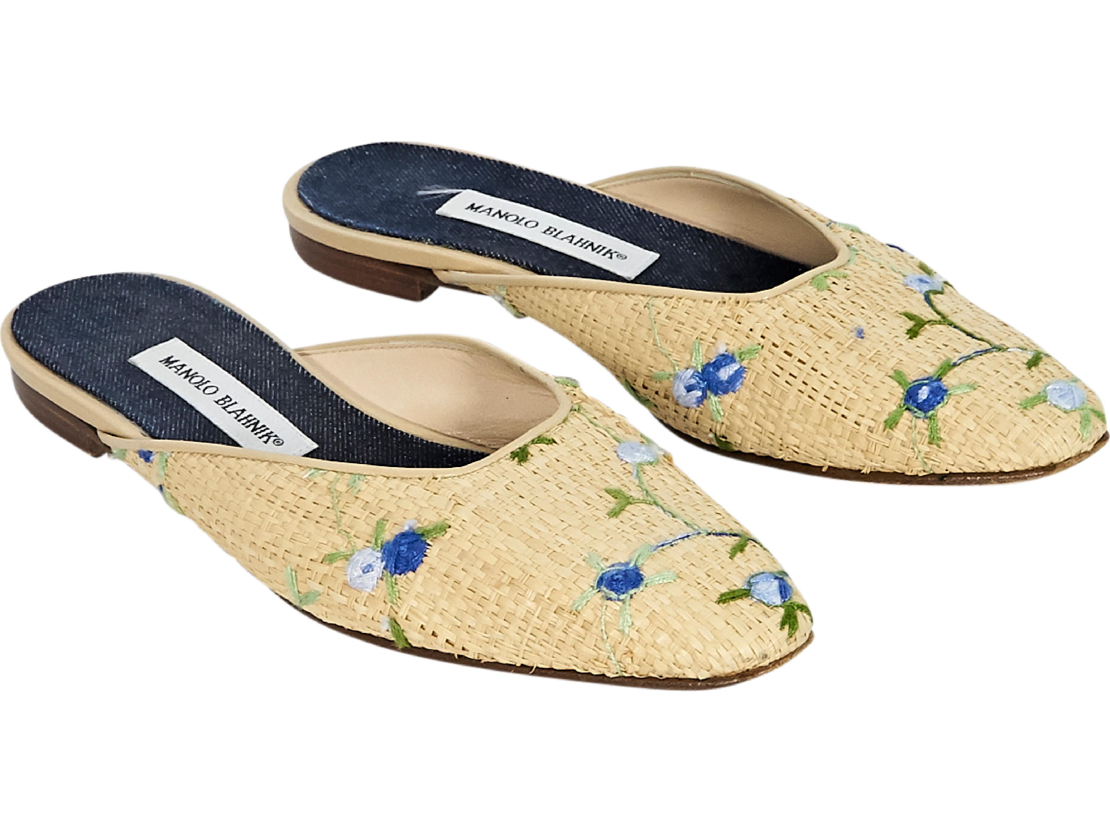 Product details:  Tan straw flat mules by Manolo Blahnik.  Features blue floral embroidery.  Round square toe.  Slip-on style. 
Condition: Pre-owned. Very good. 
Est. Retail $ 745.00