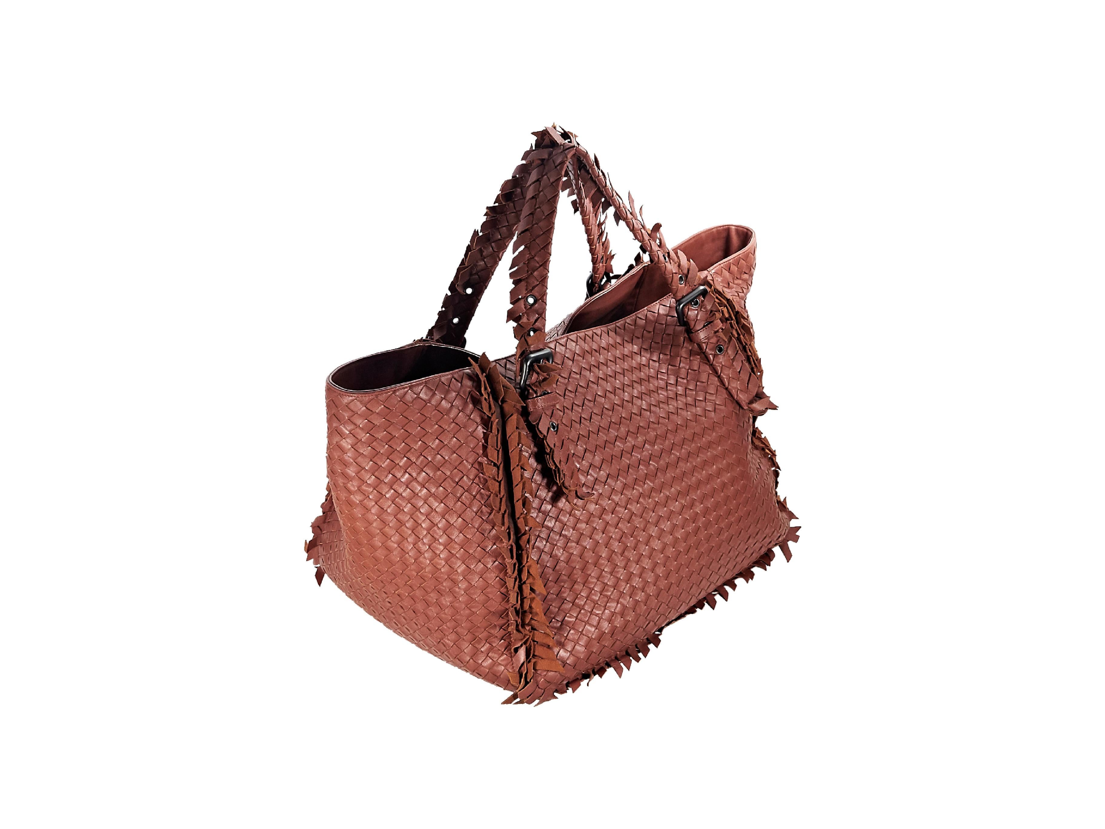Product details:  Rust nappa leather intrecciato large tote bag by Bottega Veneta.  Features fringed trim.  Dual adjustable shoulder straps.  Open top.  Lined interior with inner zip and slide pockets.  Antiqued silvertone hardware.  Dust bag