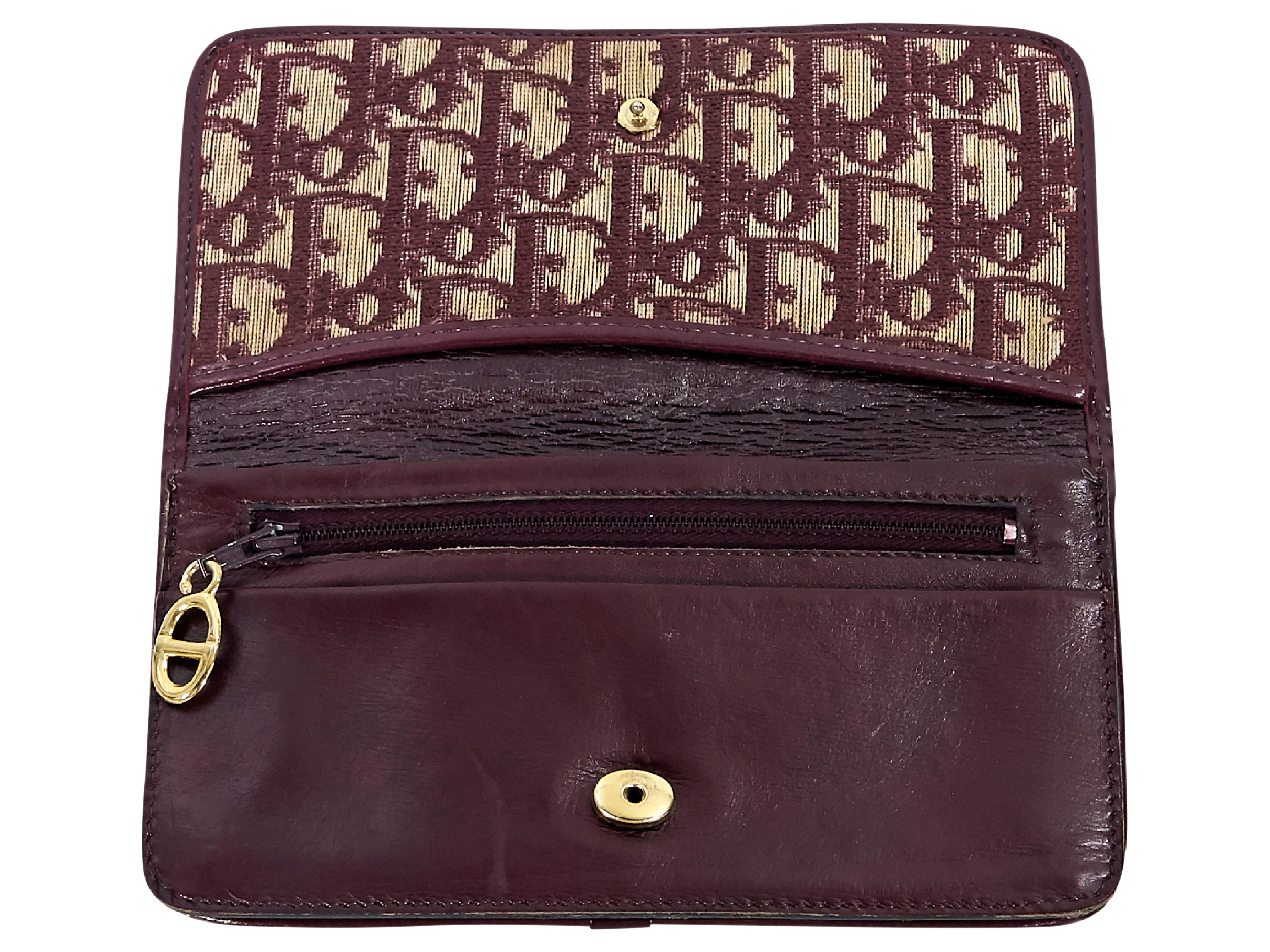 Product details:  Vintage burgundy monogram wallet by Christian Dior.  Front flap with concealed snap closure.  Lined interior with inner zip pocket.  Goldtone hardware.  7.25
