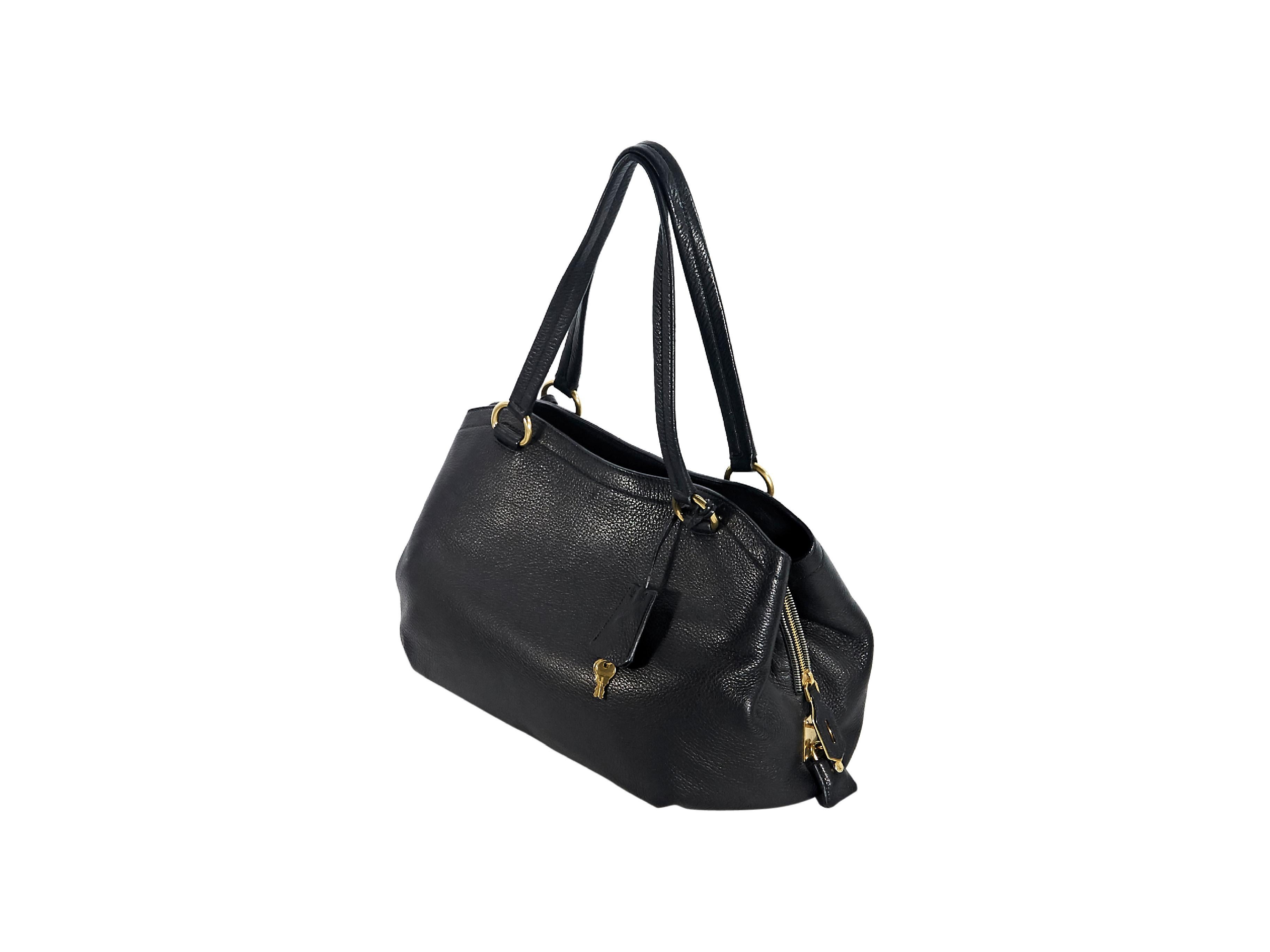 Product details:  Black leather Vitello shopper tote bag by Prada.  Dual shoulder straps.  Two snap compartments and one center zip compartment with lock and key.  Lined interior with inner zip pocket.  Side snap gussets.  Protective metal feet. 