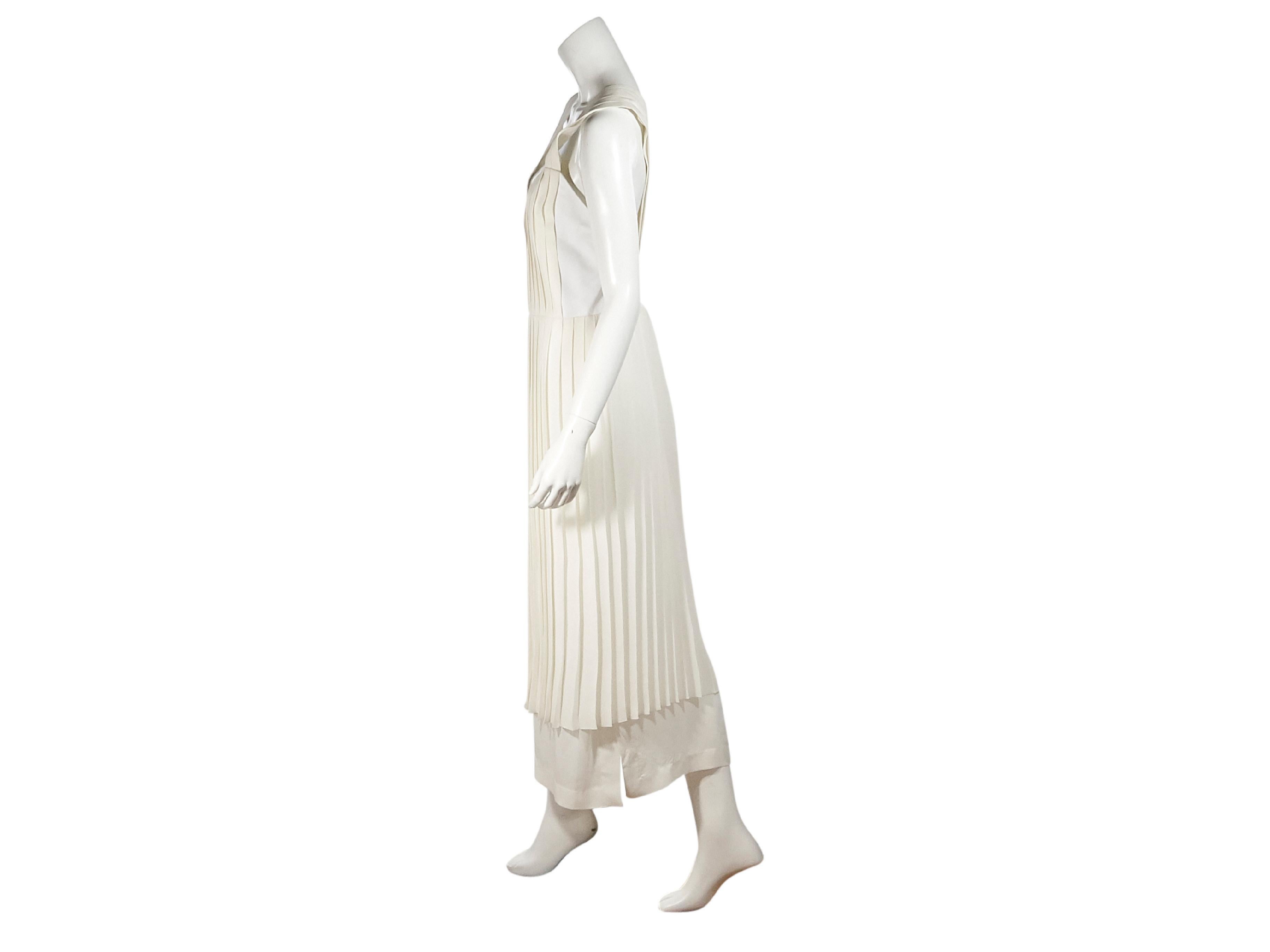 Product details:  White pleated silk dress by Edun.  V-neck.  Sleeveless.  Crossback straps.  Layered hem.  Concealed closure.  30.5