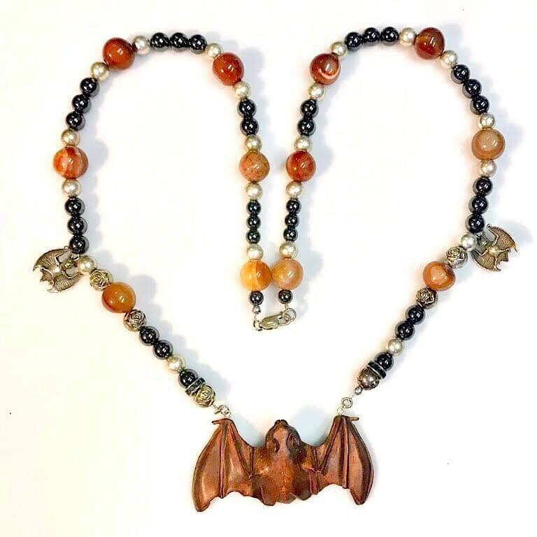 This ensemble is my own playful creation. It has a beautifully hand carved found netsuke bat pendant. The pendant is hard wood with inlaid black stone eyes. It hangs from a necklace made of figured agate, hematites, smooth silver and textured beads.