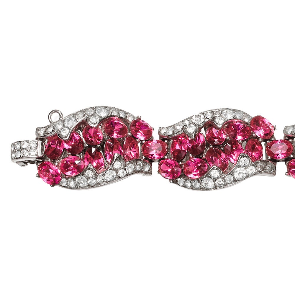 Exquisite rhodium plated Trifari bracelet, featuring bright fuchsia pink oval rhinestones, the colour of pink tourmalines which are flanked on each side by a border of crystal rhinestones.

The bracelet is articulated and made up of 7 panels and