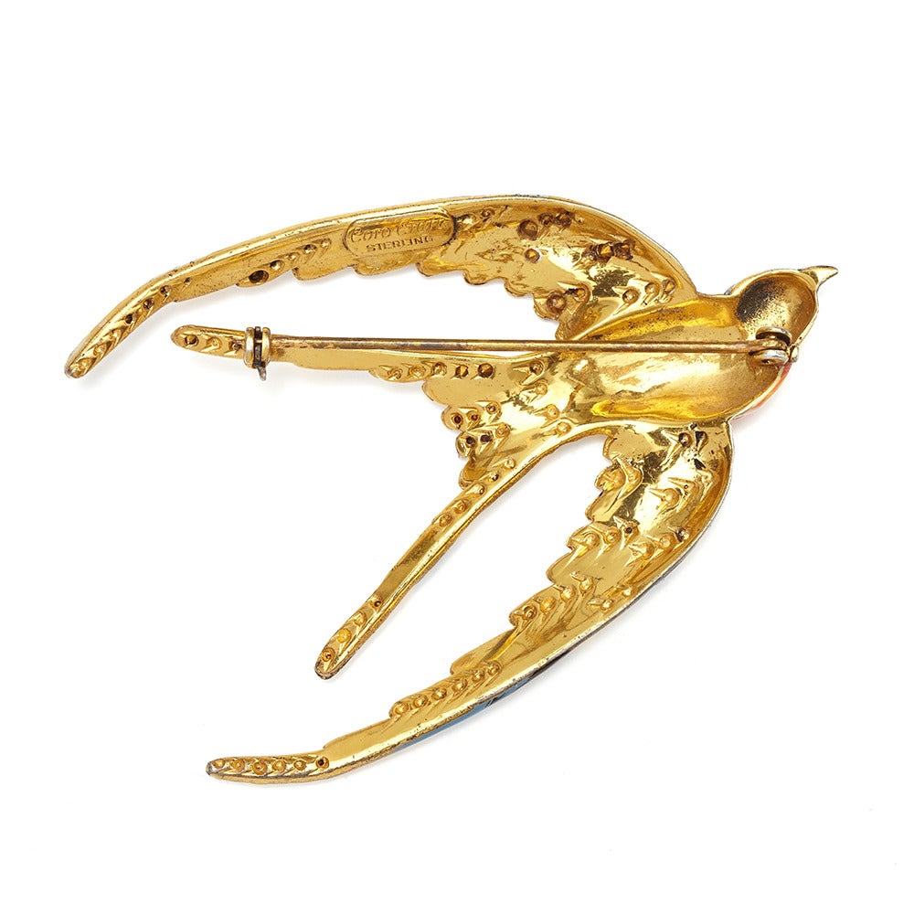 A beautiful swallow brooch, made by Coro and patented by Adolf Katz, in 1943.
The brooch is Goldplated over Sterling Silver and finished with hand painted enamel details. It is embellished with clear crystal rhinestones.

Wartime jewellery pieces