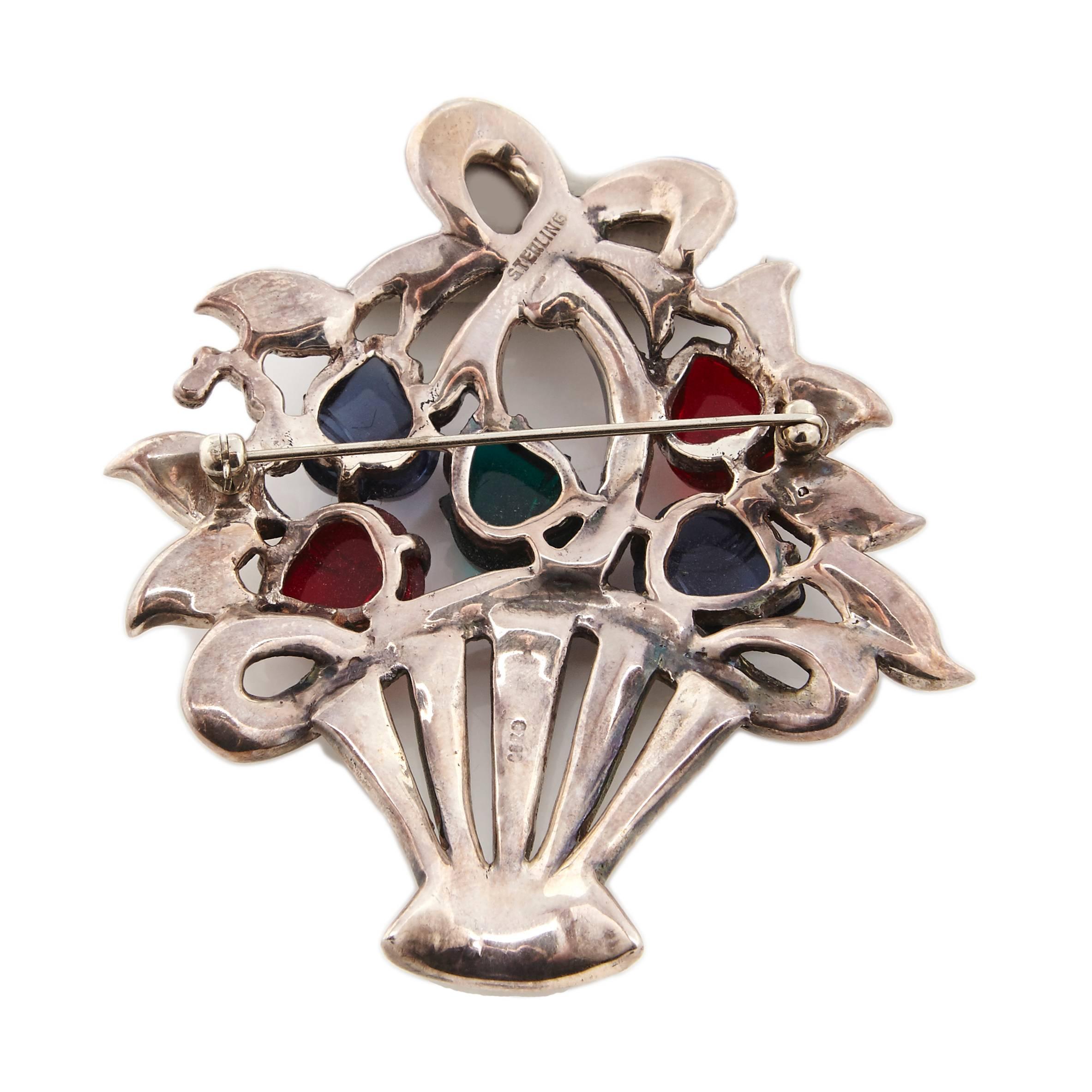 A large Sterling Silver basket brooch of fruit salad stones designed by Coro. The basket itself is set with clear crystal rhinestones and topped with a bow. 

Marked: Sterling and Coro on the reverse.

Inspired by Cartier's Tutti Frutti jewellery