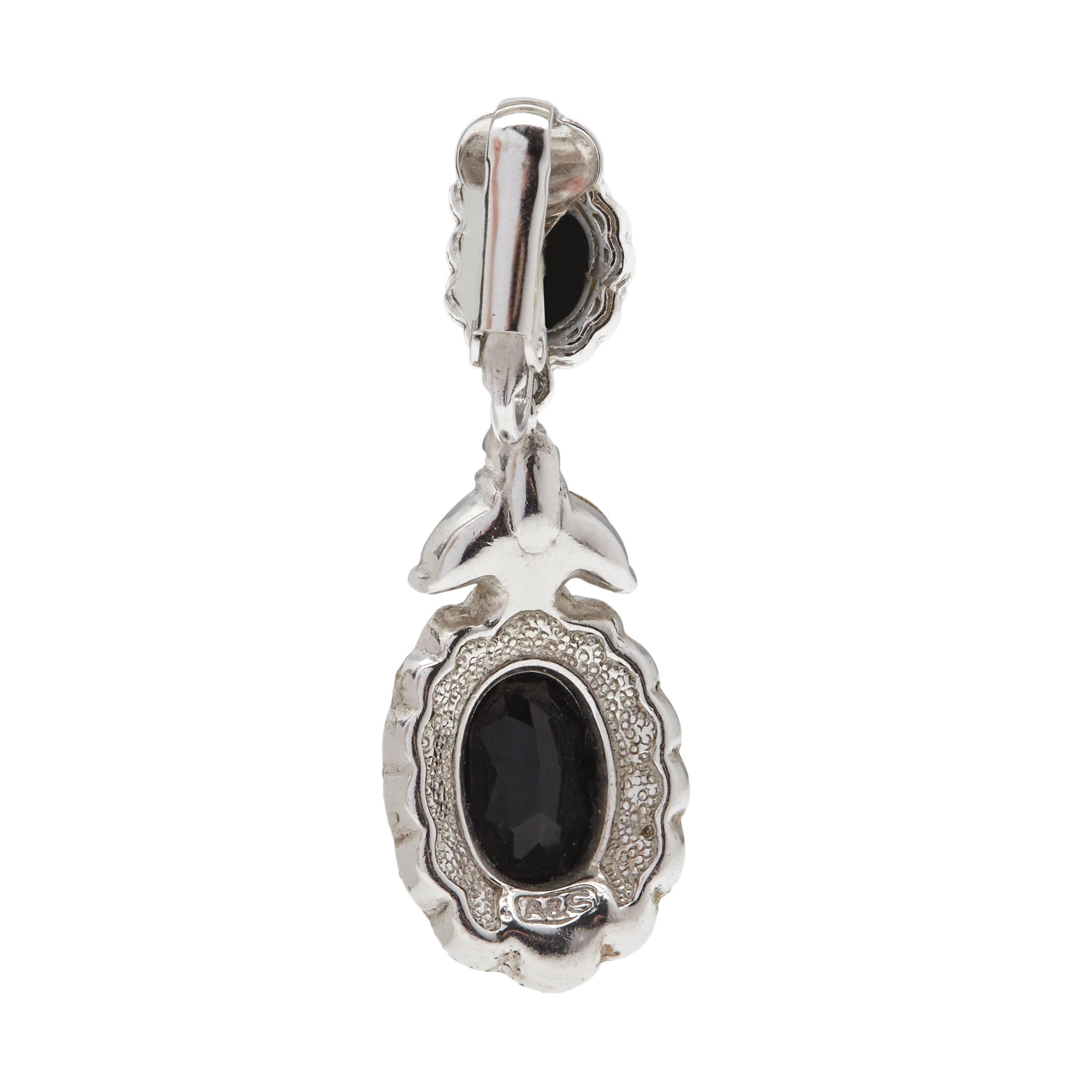 These silver plated clip-on oval earrings are embellished with round-cut clear Swarovski crystals and central prong-set oval-shaped faux Jet Swarovski crystals. They measure 4.5cm long and 1.5cm at their widest point.

Marked: A & S

Attwood &