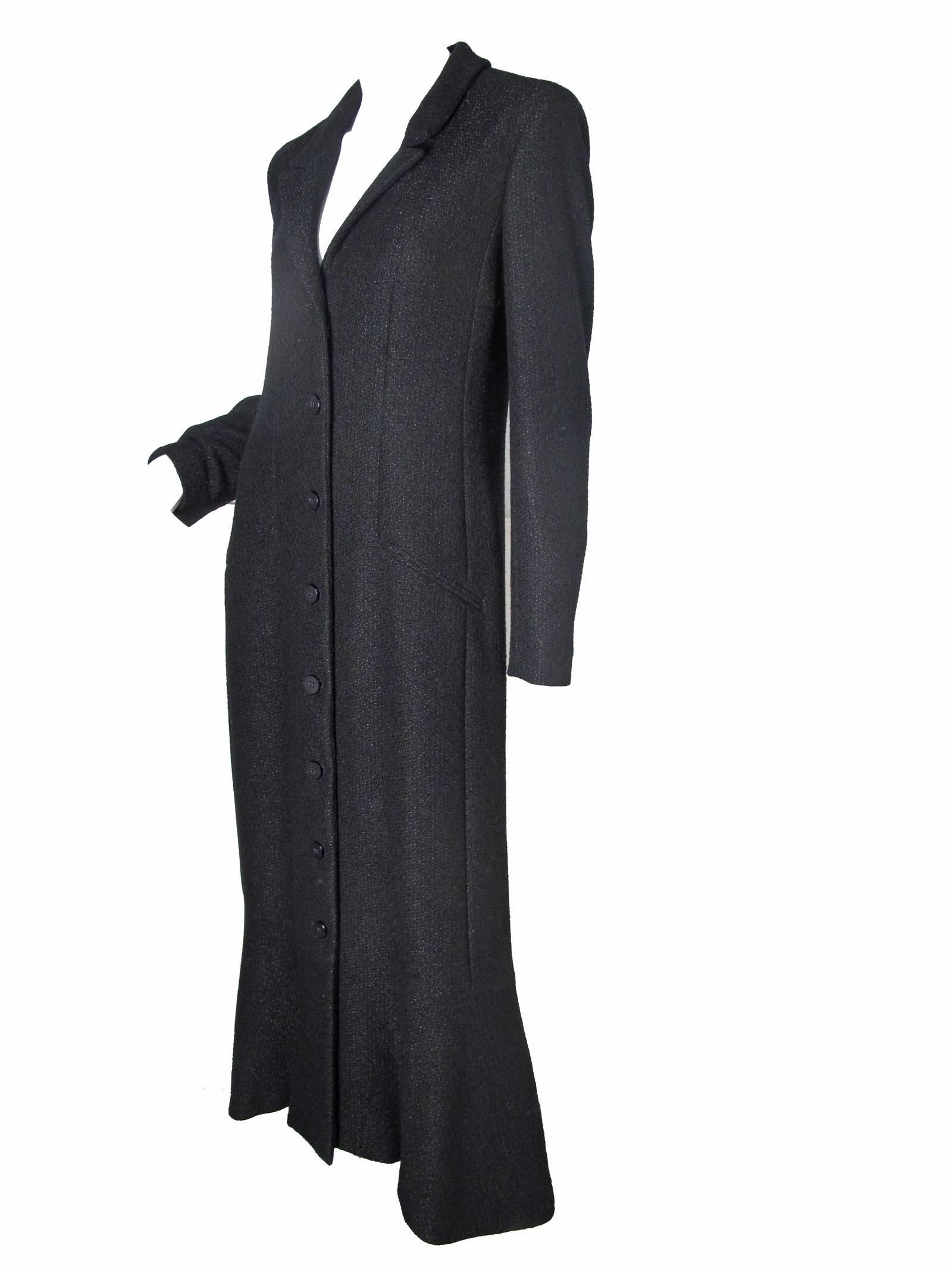 Chanel black coat dress with ruffle hem, buttons down front.  Two front pockets. Condition: Excellent, comes with extra fabric swatch and two extra buttons.  Wool, nylon fabric. Size 40

38