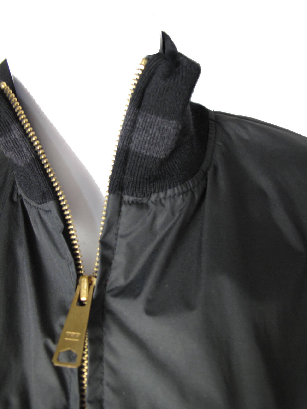 1990s Jean Paul Gaultier black nylon and cotton bomber jacket with black and grey knit collar and cuffs.  Silk and acetate lining. Condition: Excellent, looks new. 

Size 8 

42