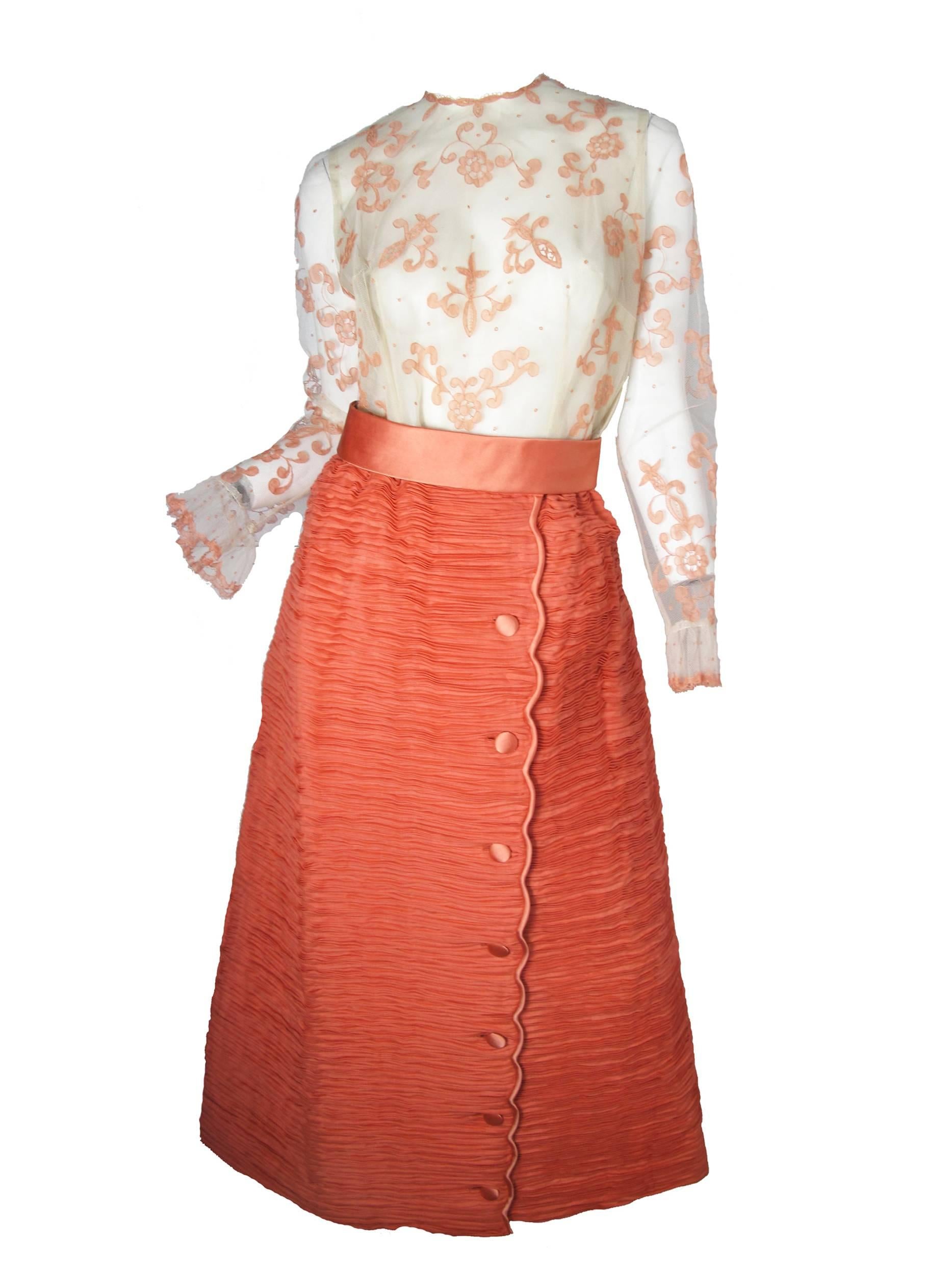 1960s Sybil Connolly labeled "softly spoken" off white mesh shirt with pink lace overlay.  Pleated Irish linen peachy/pink skirt with buttons down front. Condition: Excellent. Size 10
Top: 36" bust, 31" waist, 42" hips,
