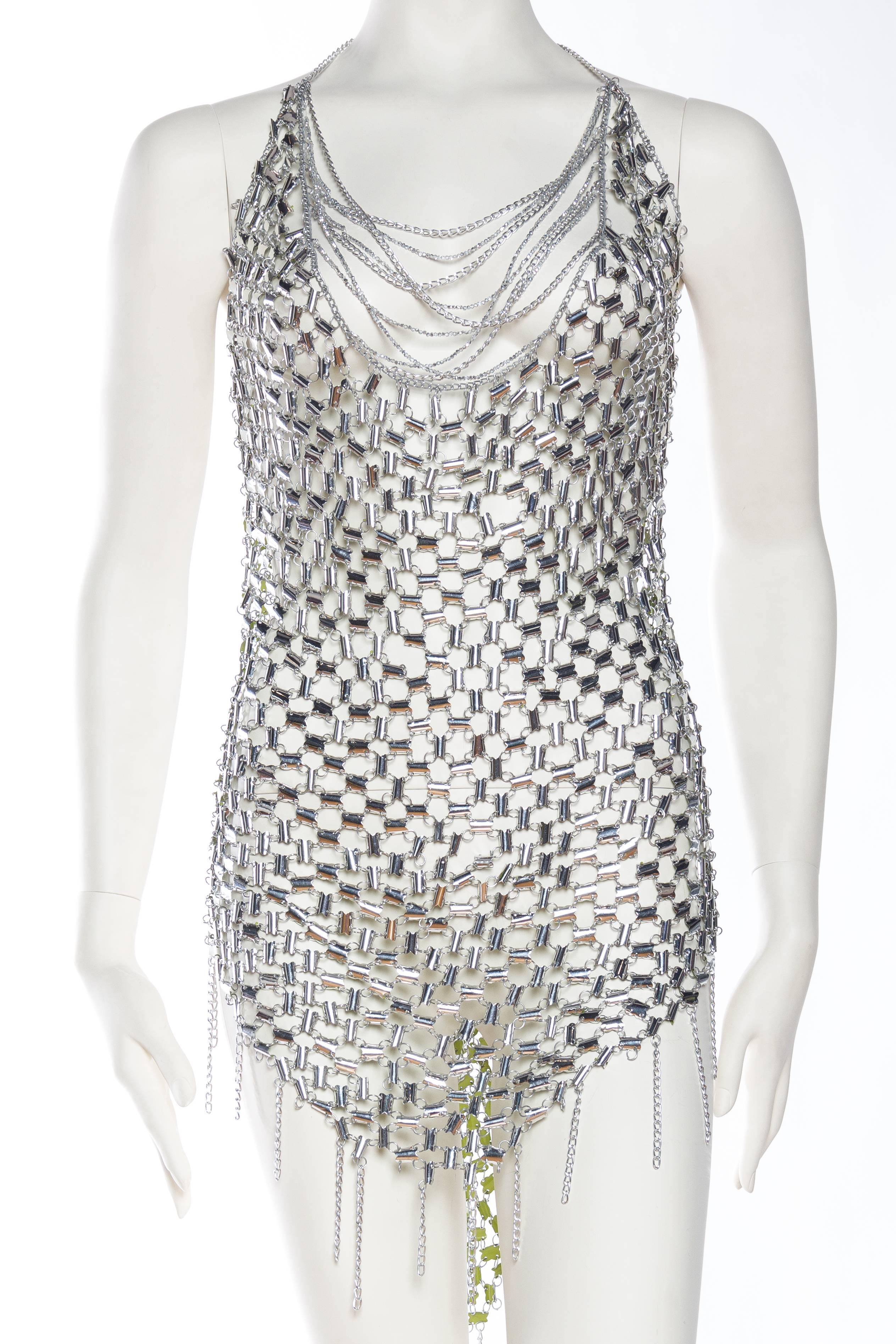 This dress looks to have been made from an original 1960s plastic and aluminum link dress attributed to Paco Rabbane. The piece has been greatly altered however with crystals and fringe. Piece is reversible to lime green.
