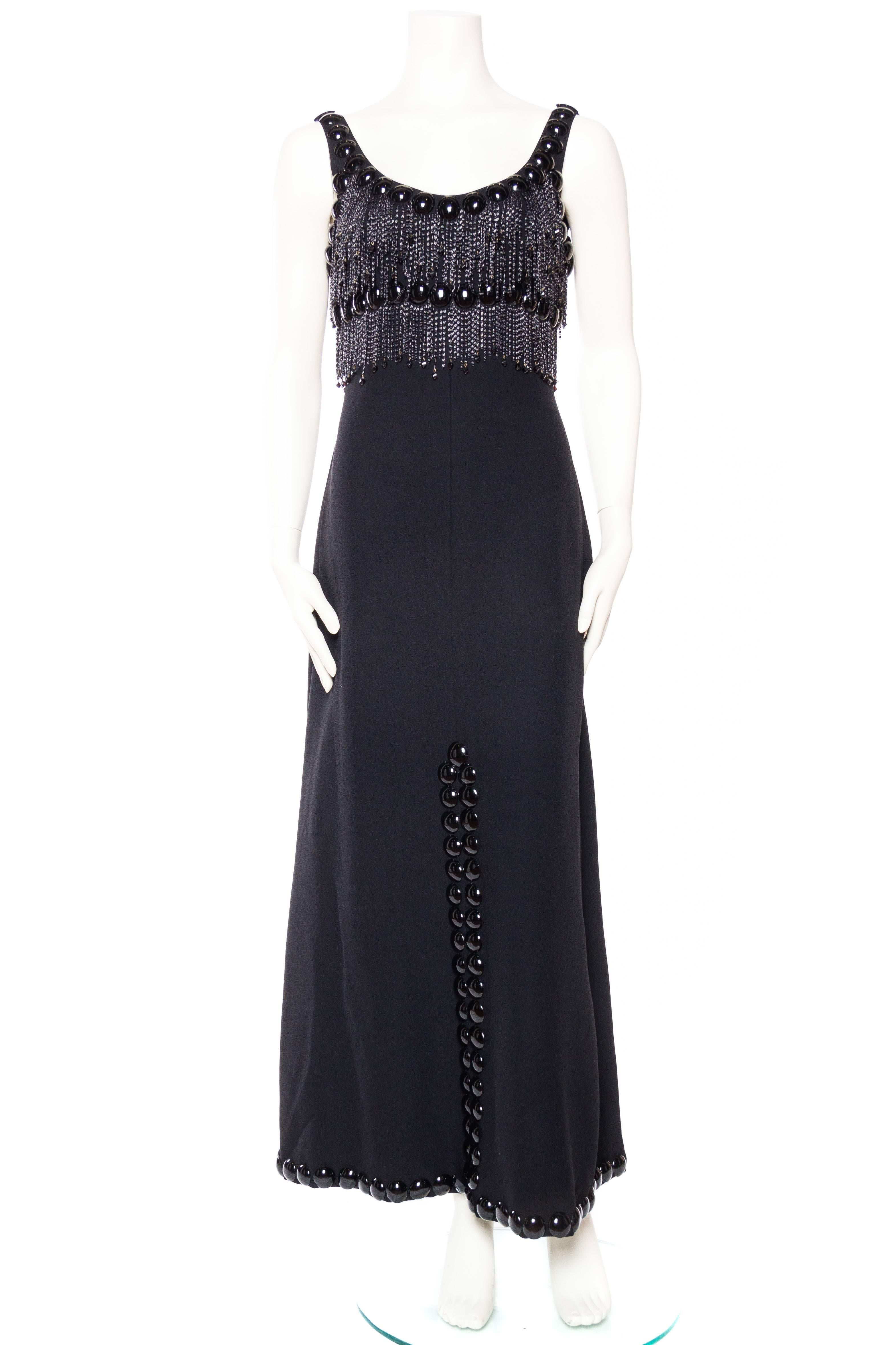 Exceptionally rare mid to late 1960s Azzaro gown with very unique embellishments, fully lined in rayon. Truly a museum grade piece. 1960S LORIS AZZARO Black Rayon Crepe Empire Waist Gown With Futuristic Domed Pailettes & Chain Fringe 