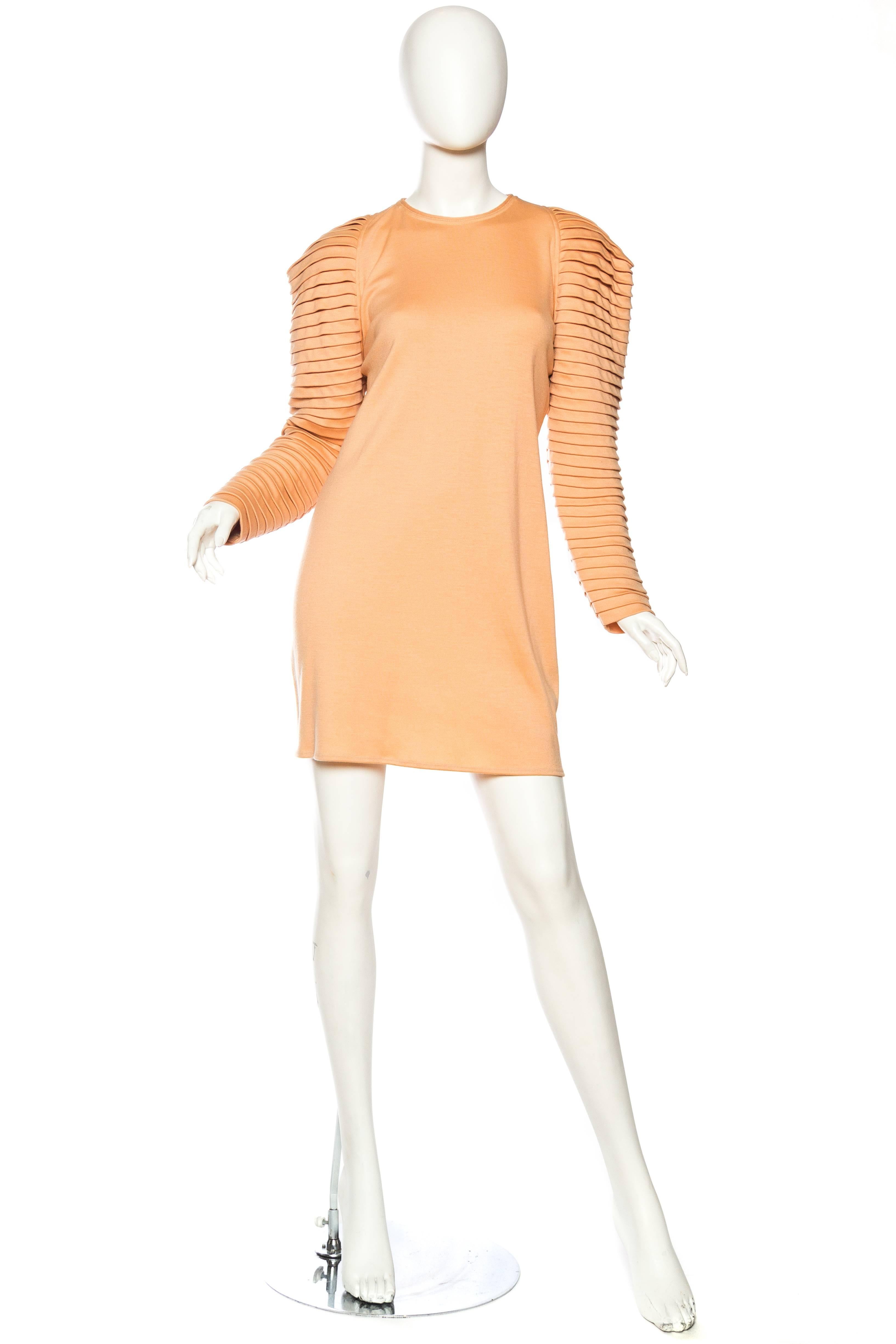 This dress dates from Gianni's early years when he was designer of the brand Genny as well as his own label. This dress is made of a wool jersey which has been cut sharp and straight away from the body with pleated sleeves creating a strong yet soft