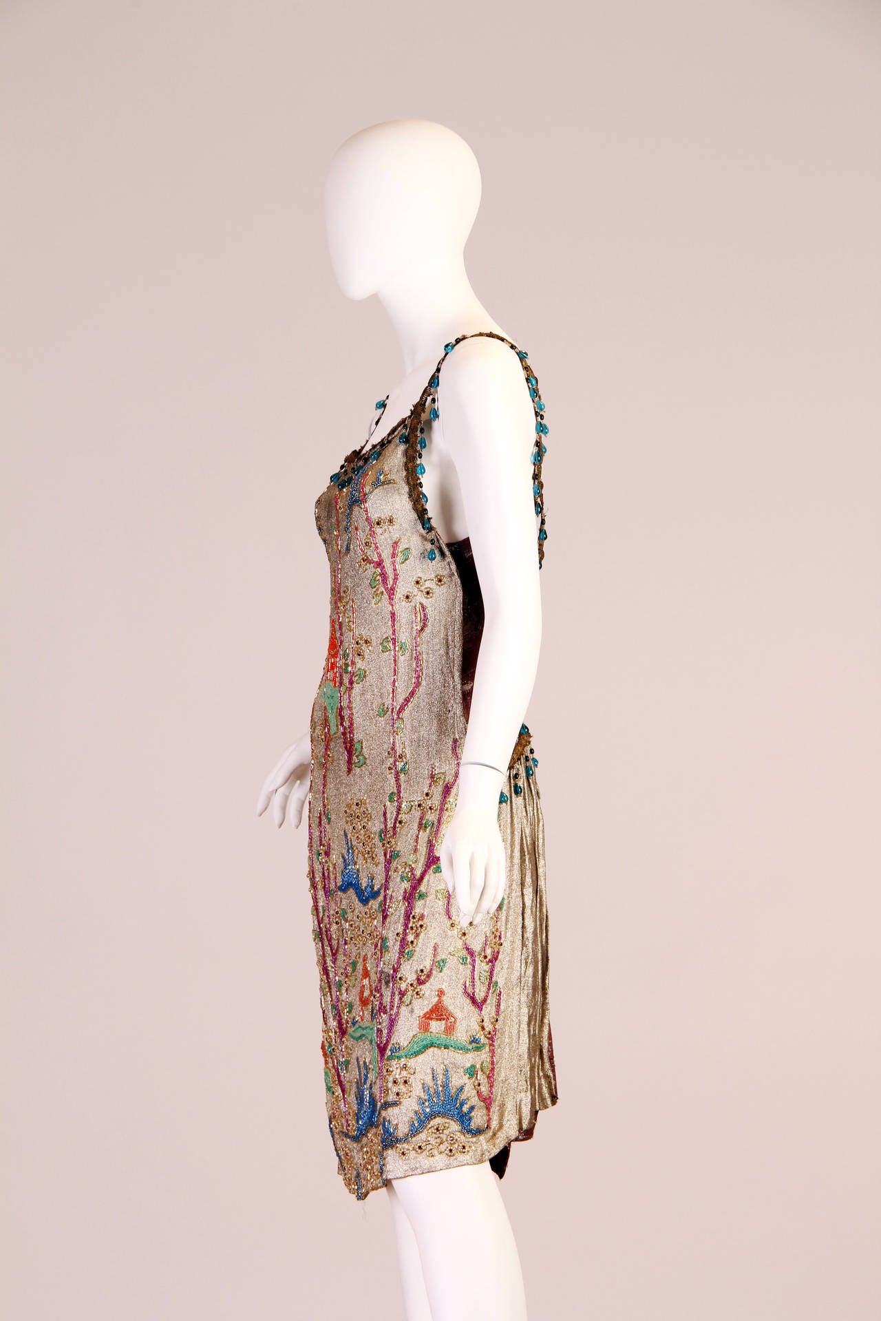 A luxurious Chinese garden scene embellishes this exotic dress from the art deco era. The bead and crystal work is all in fantastic condition. The fabric as well is very strong for its age and we would say this dress is 100% wearable. Please note