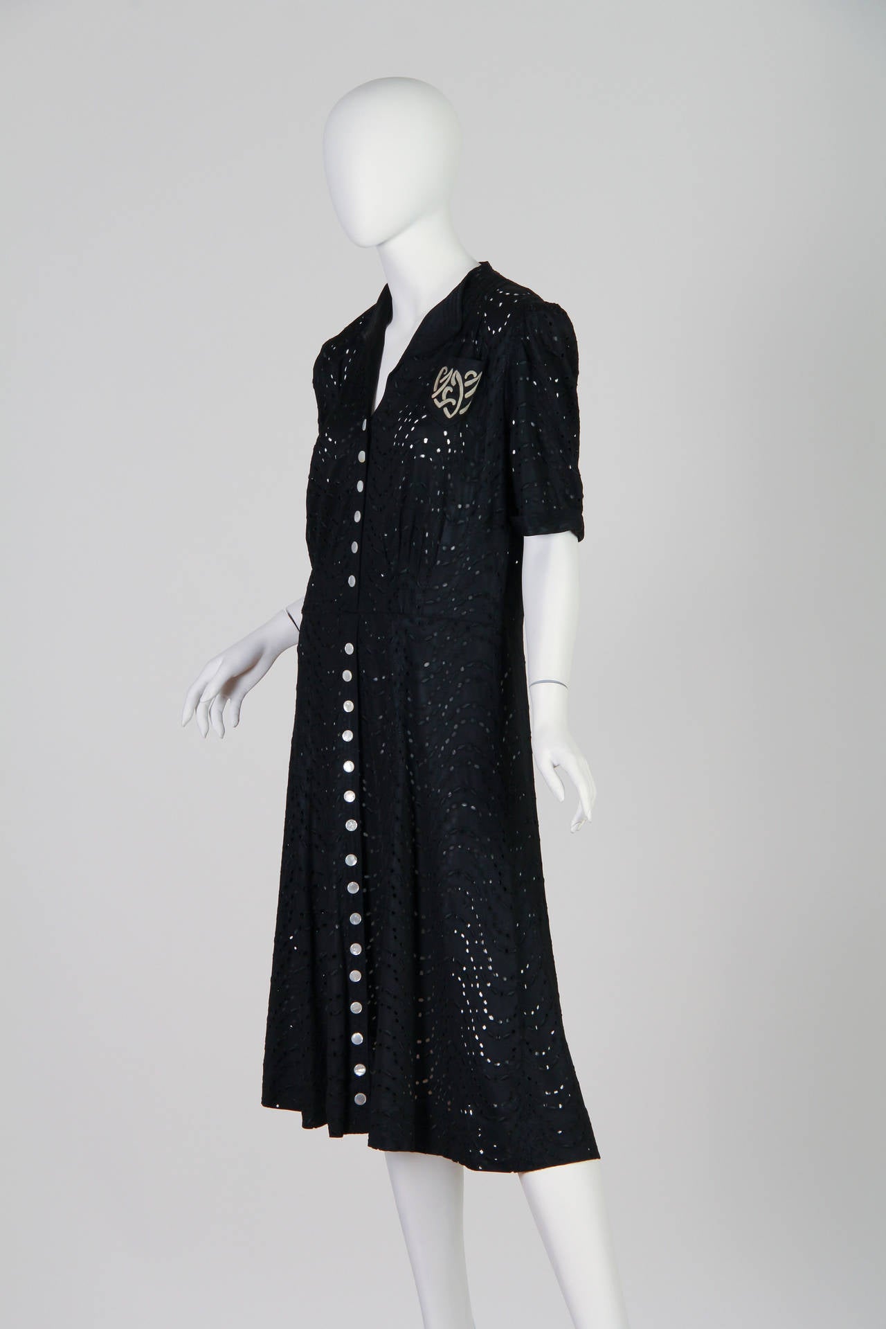 Fabulous dress in fabulous condition. The dress is either a rayon or silk jersey with an all over eyelet lace embroidery. Dating to the mid to late 1930s with beautiful original mother of pearl buttons.