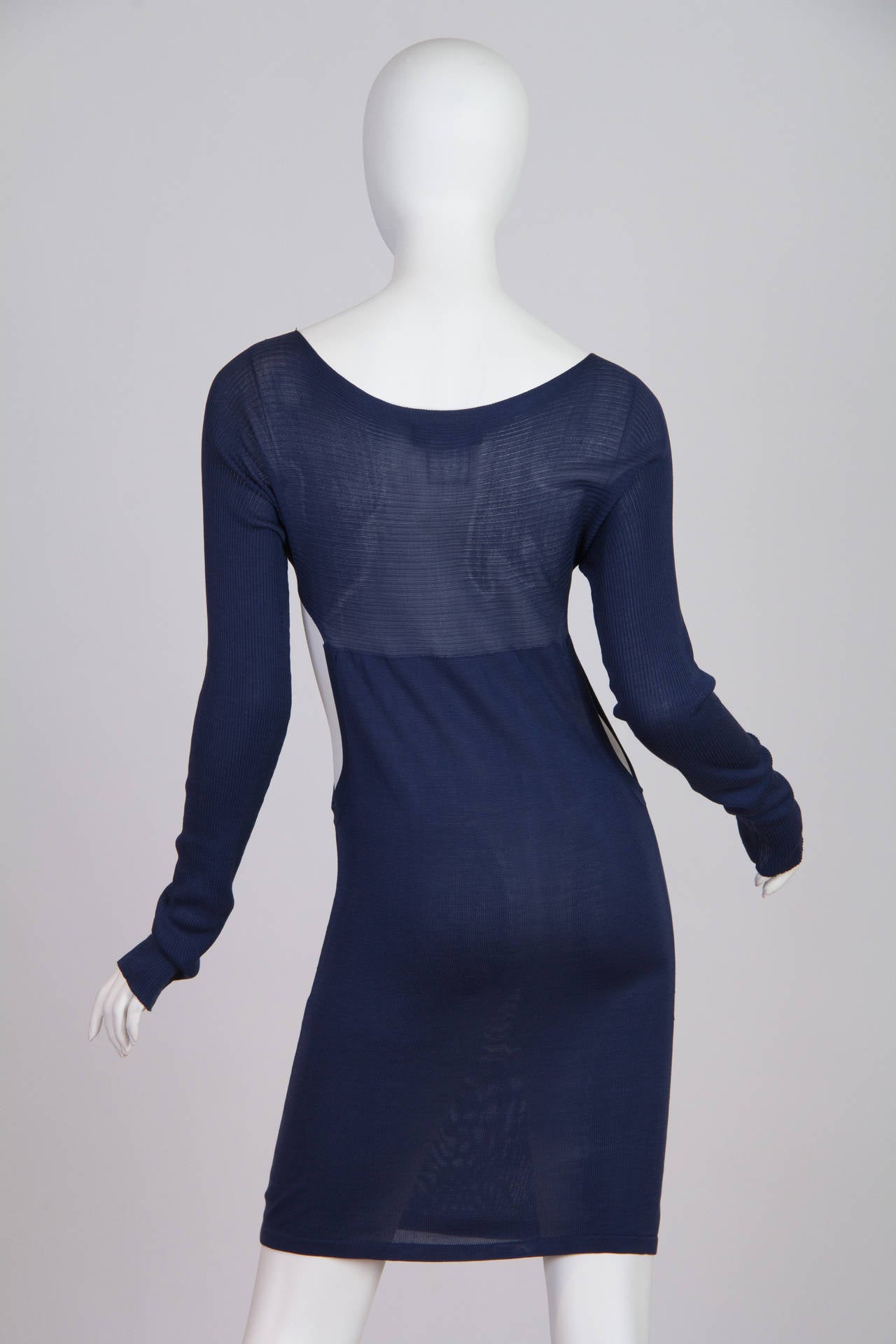 This is a long-sleeved semi-sheer sheath dress in navy blue, made of 100% silk. Large cutouts on the sides add interest and increase the dress’s layering possibilities, while adding edge to an otherwise-classic shape. The flattering neckline and