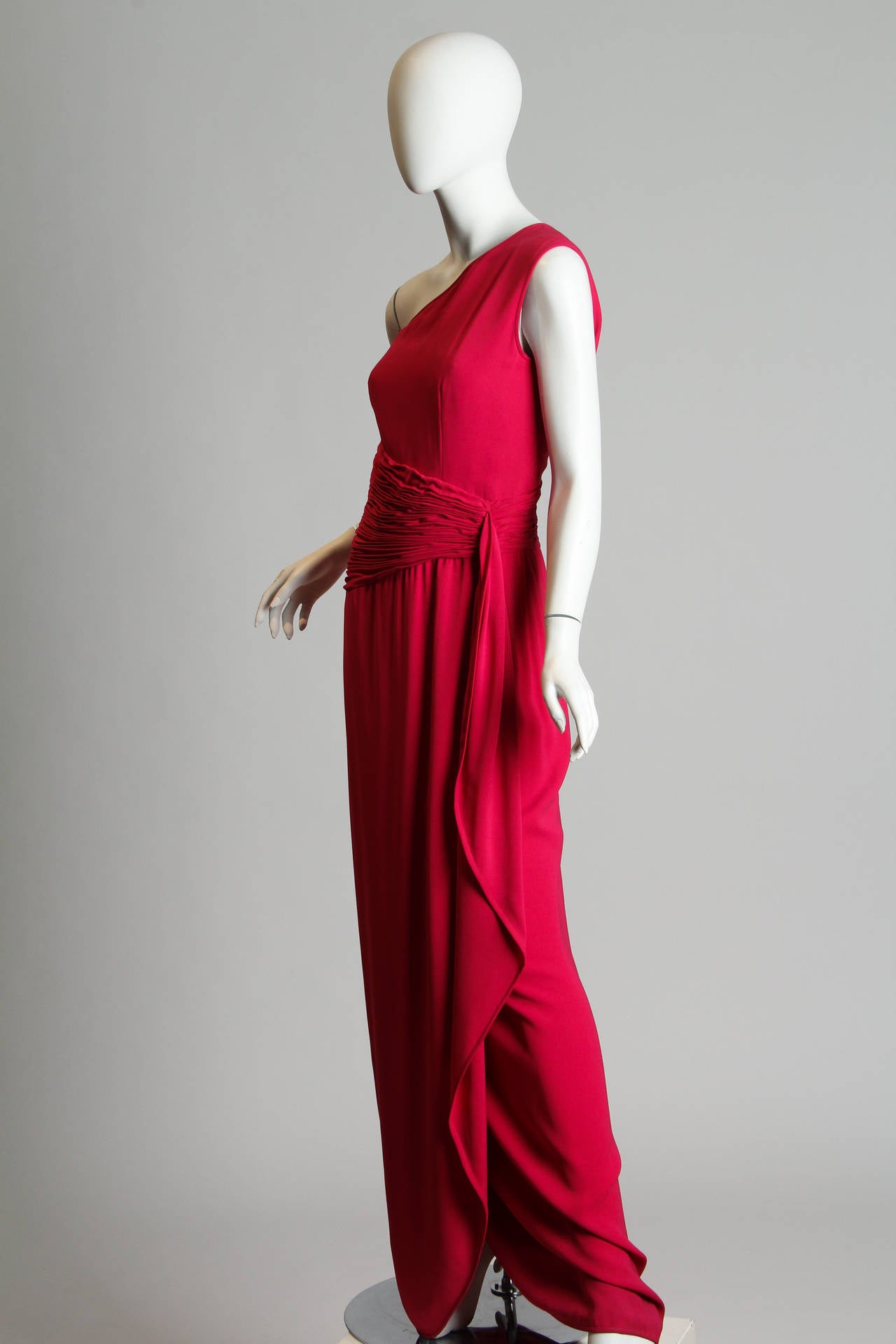 This striking pink gown is made in Italy by Valentino's Boutique collection for Bergdorf Goodman New York. The design plays with diagonals and angles, with a one-shoulder neckline, an asymmetrical ruched waistband, and a skirt which falls back on