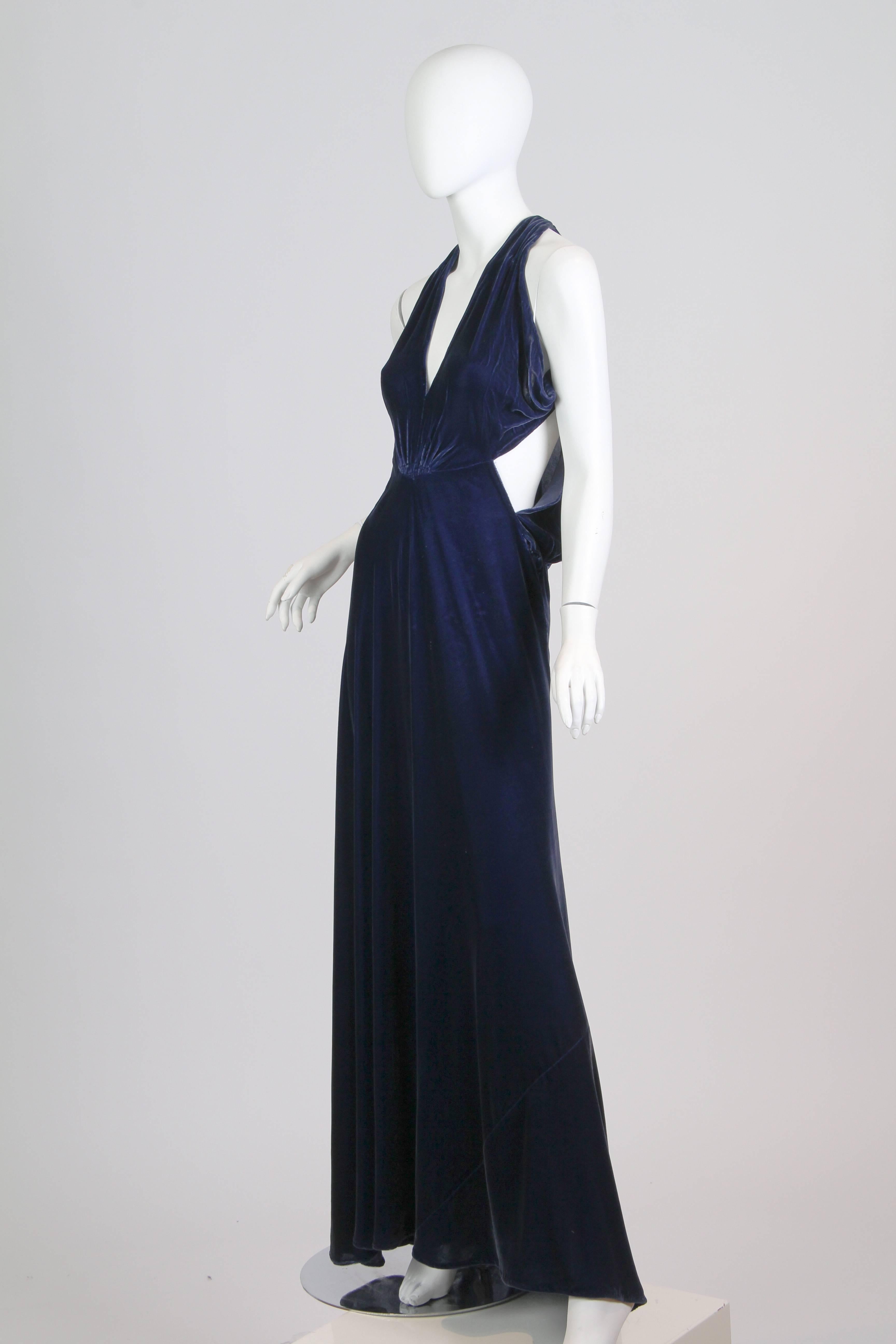 This is a stunning gown from the 1930s. Made of an incredible royal blue silk velvet, it exhibits all the most elegant design features of the inter-war period. A halter neckline in the style of Vionnet flows over the bust and into a gathered,