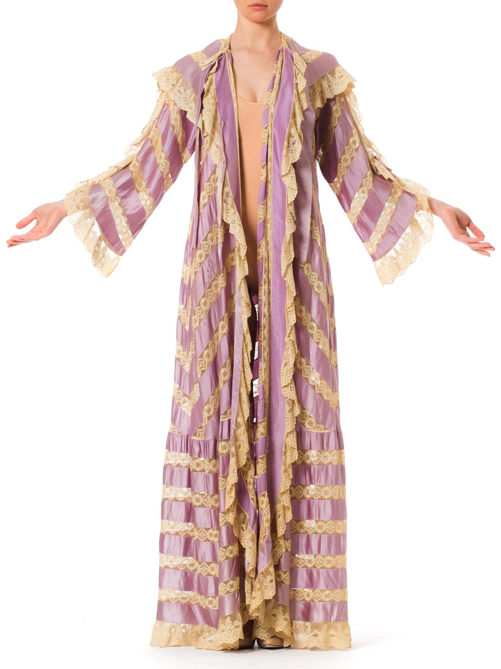 This is an incredibly beautiful peignoir from the turn of the 20th century, dating to c. 1900-1905. Made entirely of stripes and chevrons of lilac silk satin ribbon, the garment is held together by insets of delicate cream lace. The ties which hold