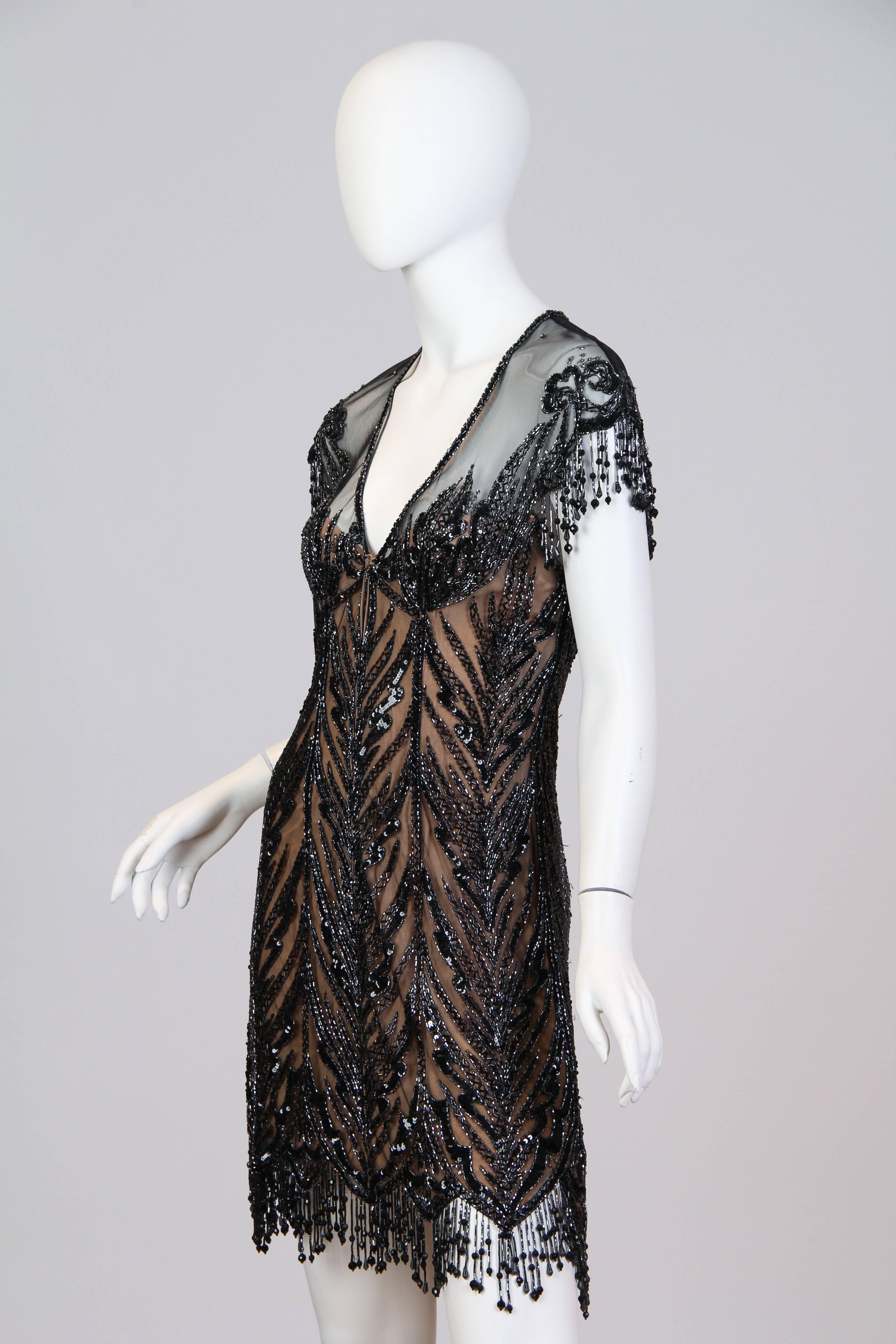 This is a stunning dress by American great Bob Mackie. Made of a sheer black net, it is highly embellished with intricate, sumptuous beadwork, sequins and crystals. With its glittering and shimmering art-nouveau pattern, low V-neck, and swinging