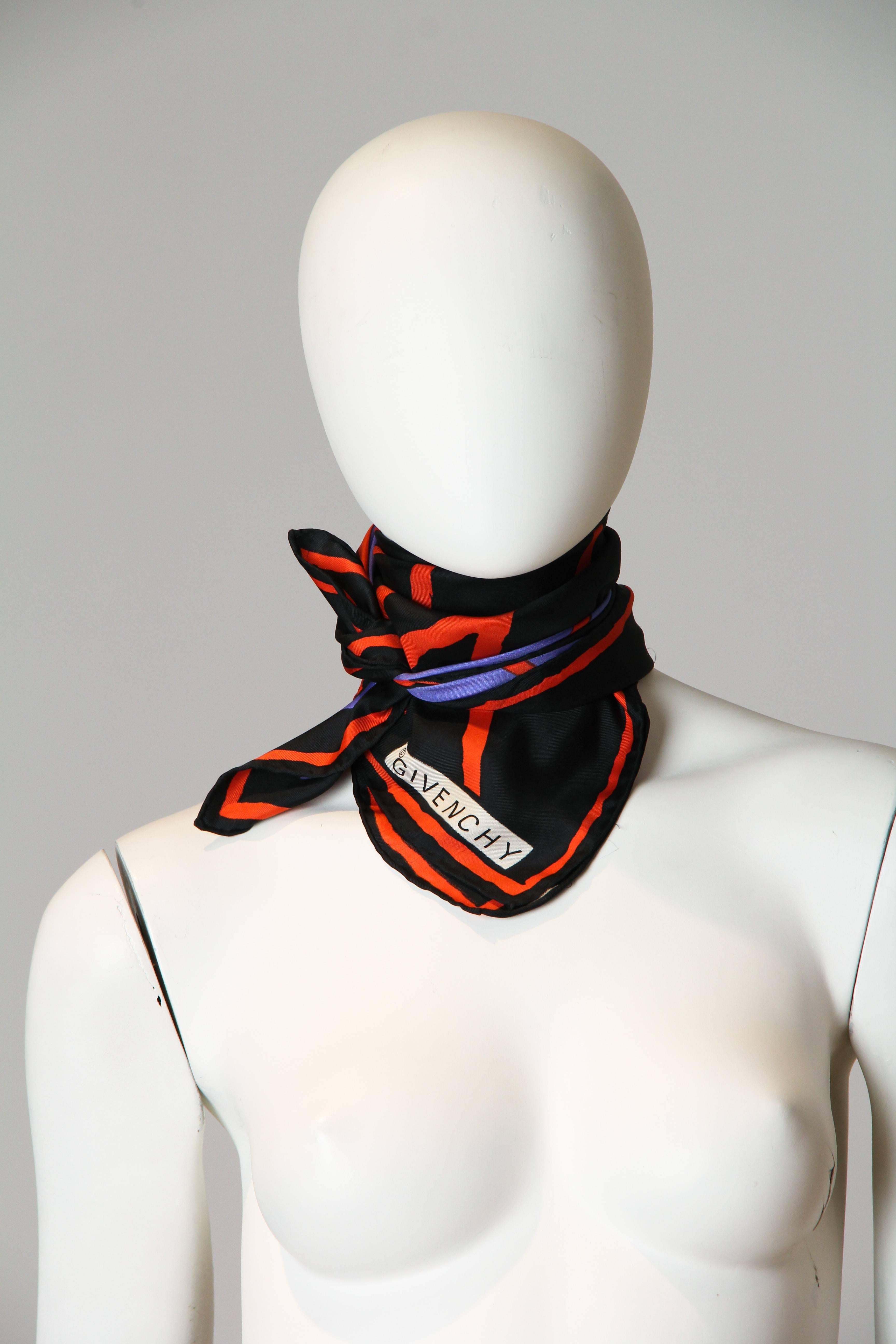 This is a classic square silk scarf by legendary design house Givenchy. In graphic blocks of periwinkle, red-orange, and black, it is perhaps the easiest-to-style statement piece there is. The colours are arranged in an abstract expressionist