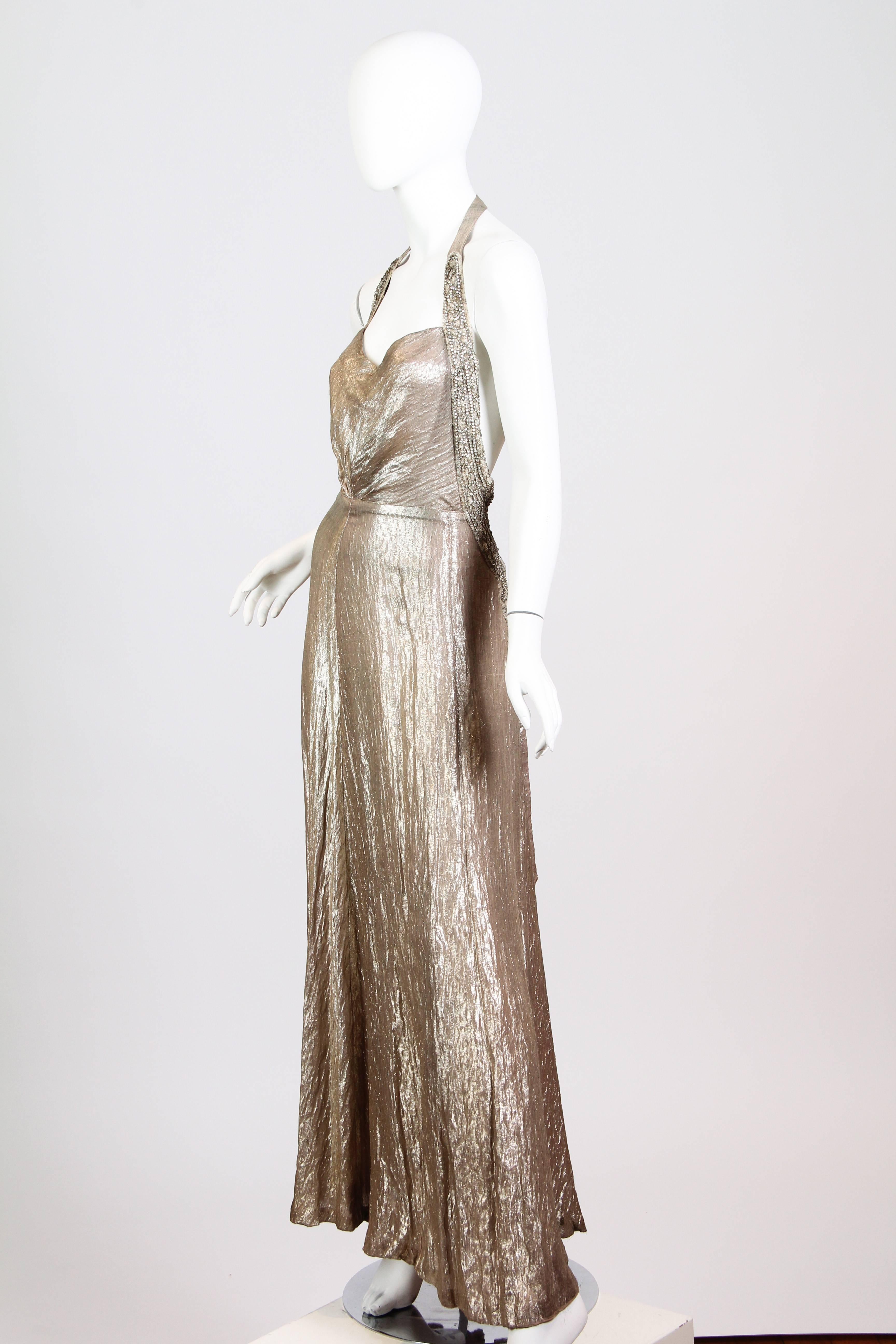 This is a stunning rose-gold silk lamé gown from the 1930s. The incredible fabric falls in gentle, crinkled flutes in front, and in a waterfall of rippling metallic silk from the double box pleat in back. The sweetheart neckline is edged by a