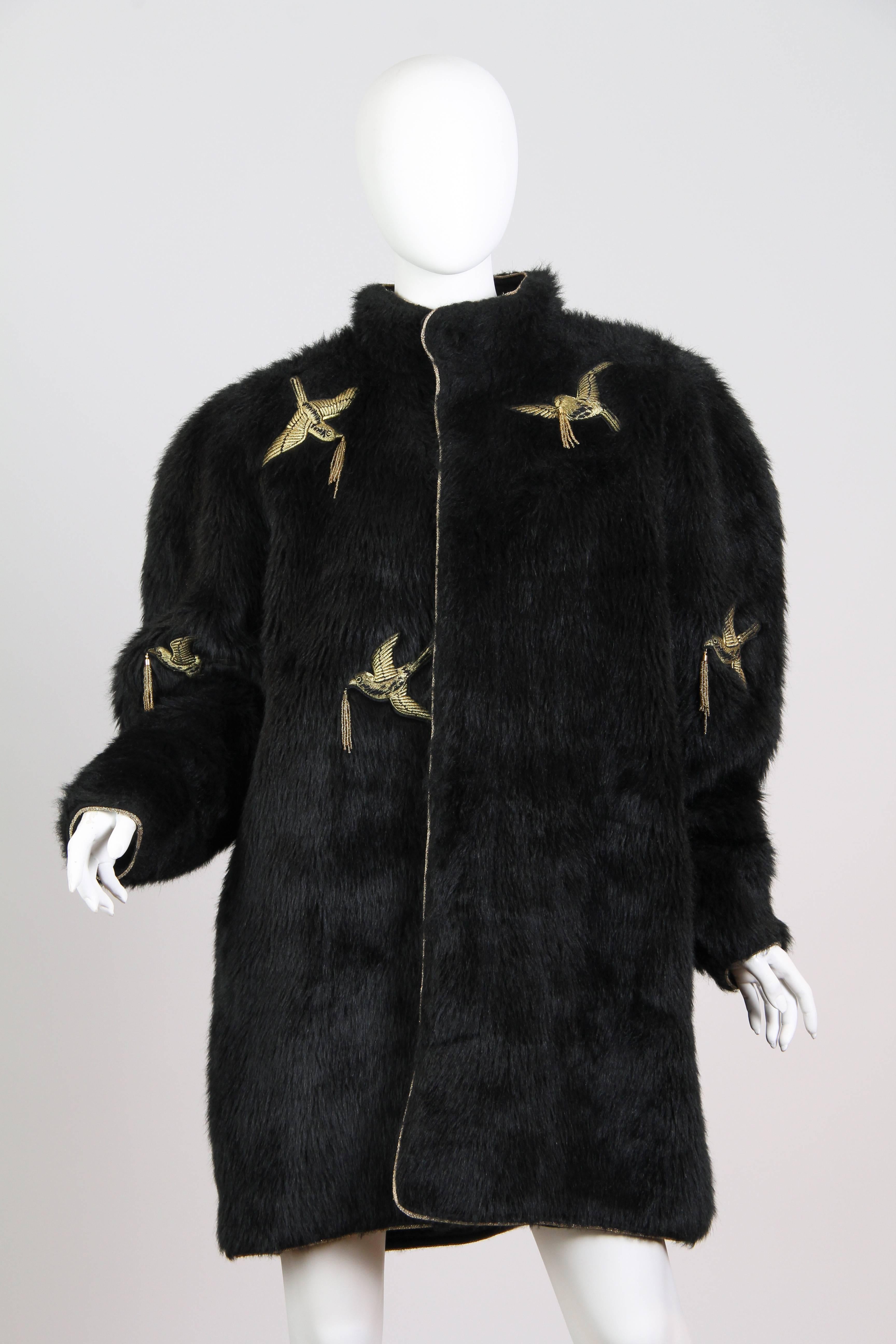 This is an incredible coat by Japanese designer Yamamoto Kansai. The base of the coat is a deep black pile, within which gold songbirds have been embroidered. Each swooping bird carries a gold beaded tassel in its beak. All the edges of the coat are